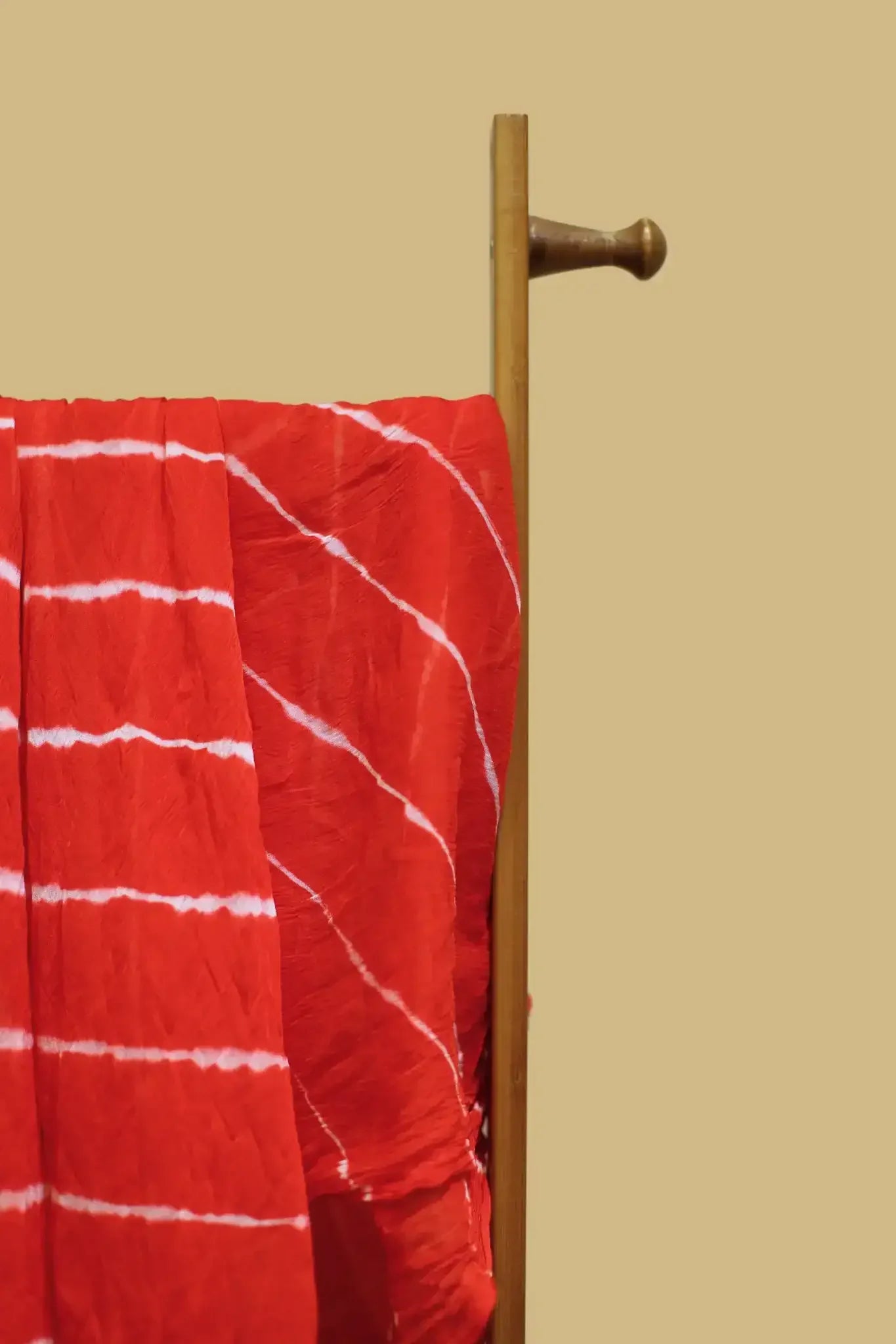Red Indian fabric with white tie-dye pattern draped on a wooden stand
