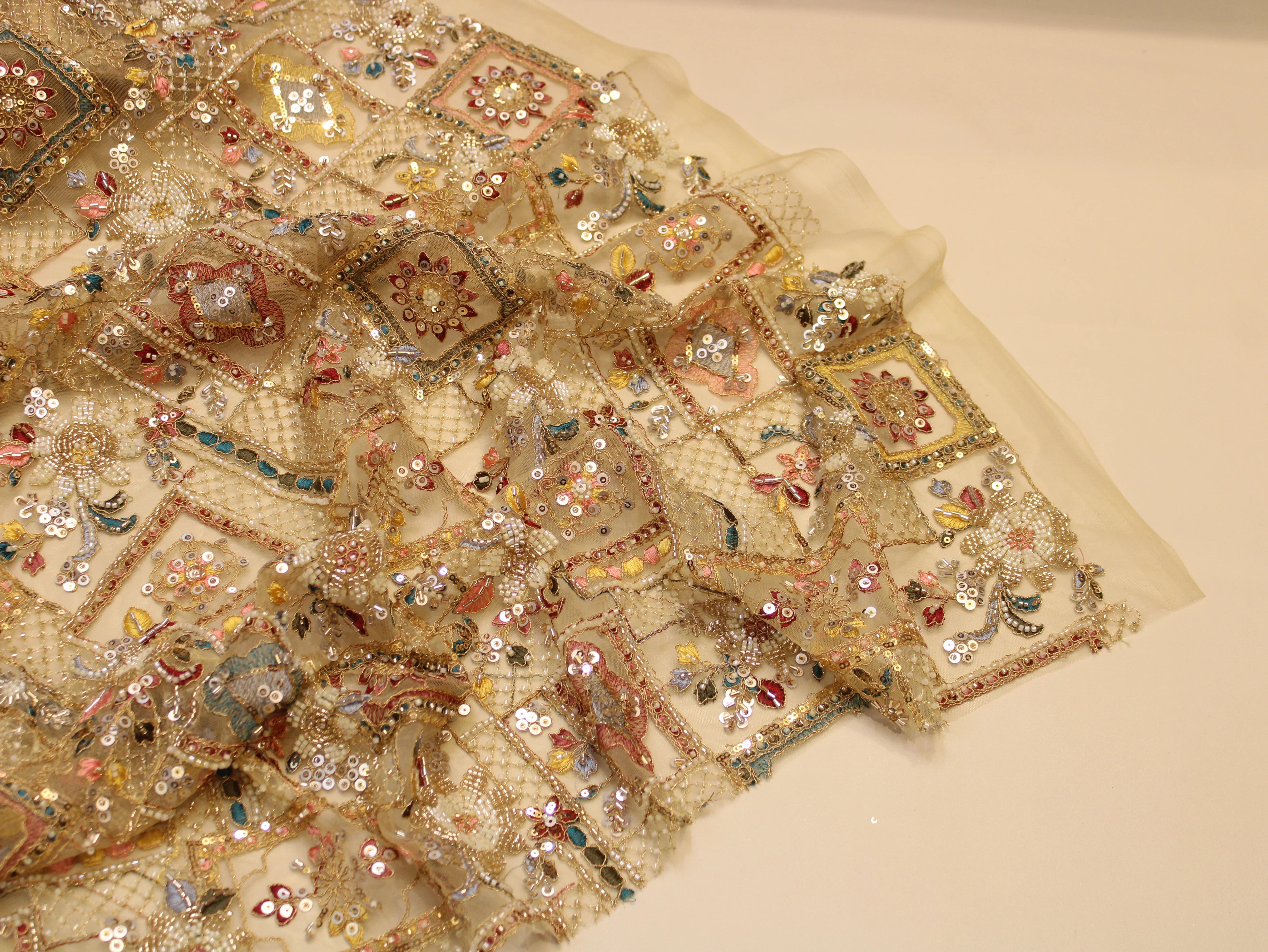 Decorative fabric with intricate beadwork and embroidery on a beige background
