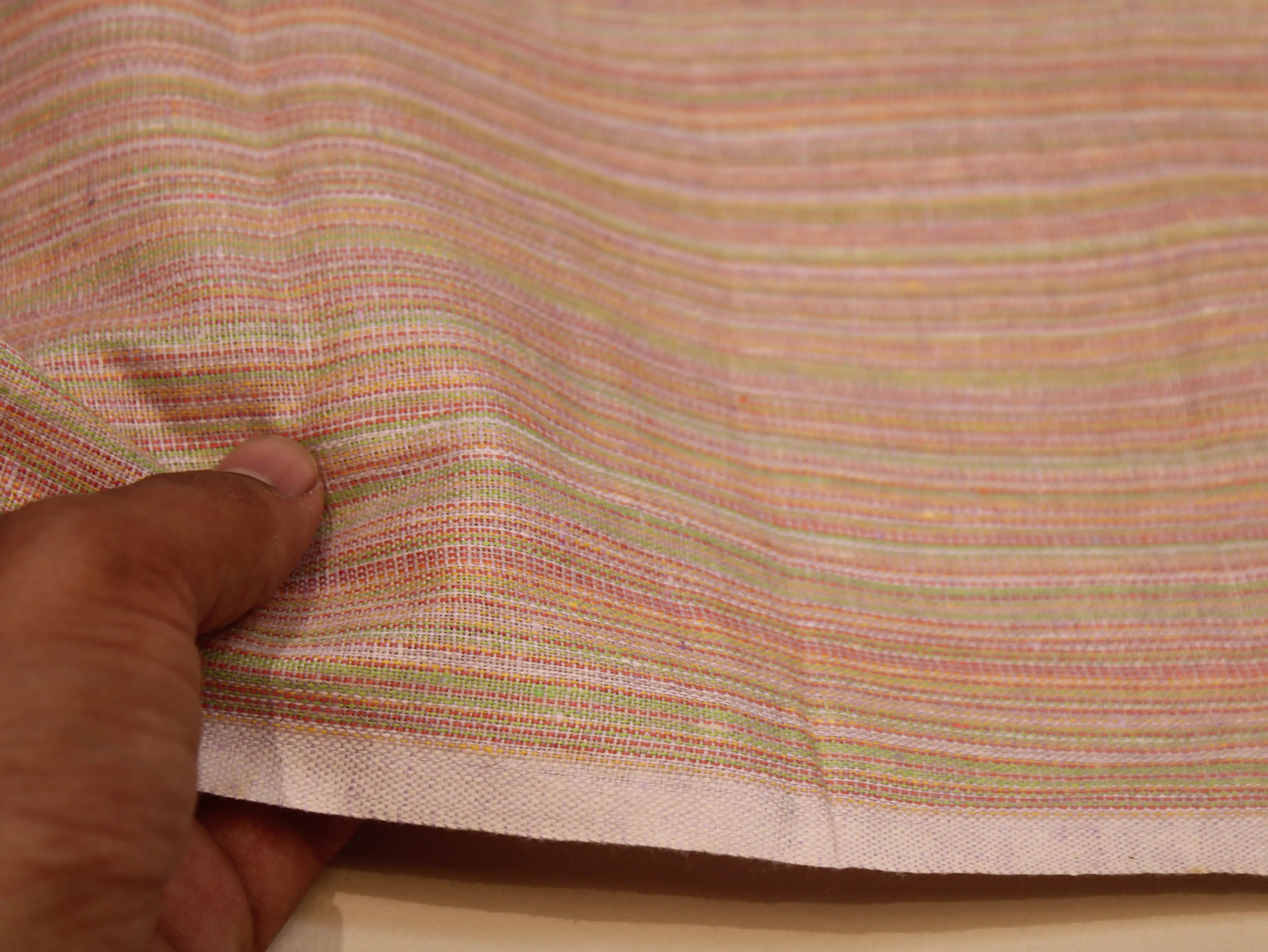 Hand holding pastel striped Indian cotton fabric with fine texture