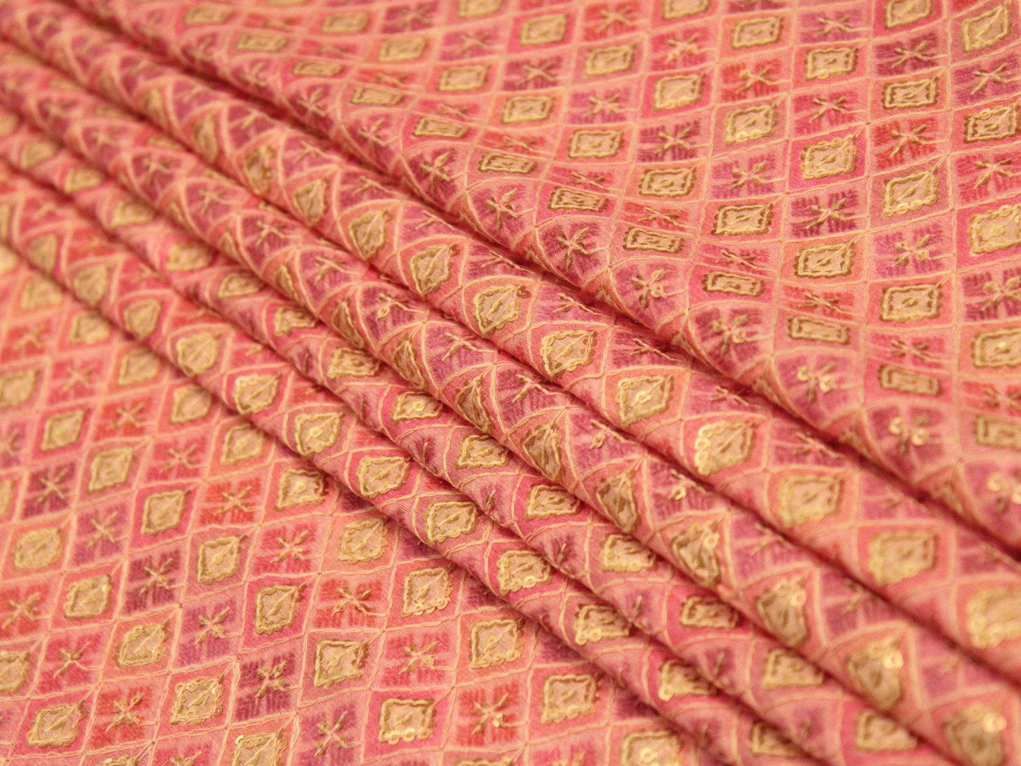Pink silk digital print fabric with gold geometric pattern, folded, close-up view