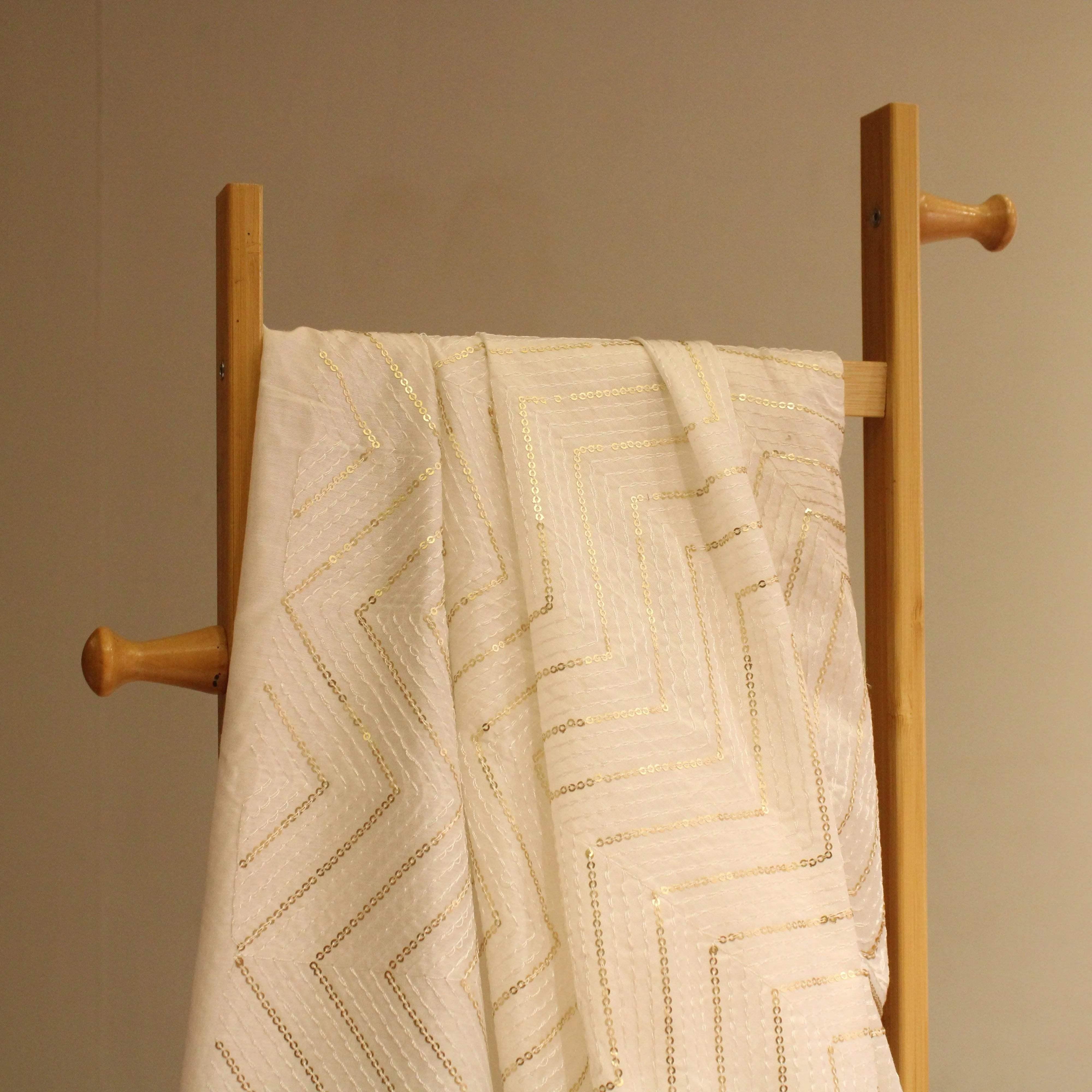 White Chanderi silk fabric with thread and sequin work draped on a wooden stand