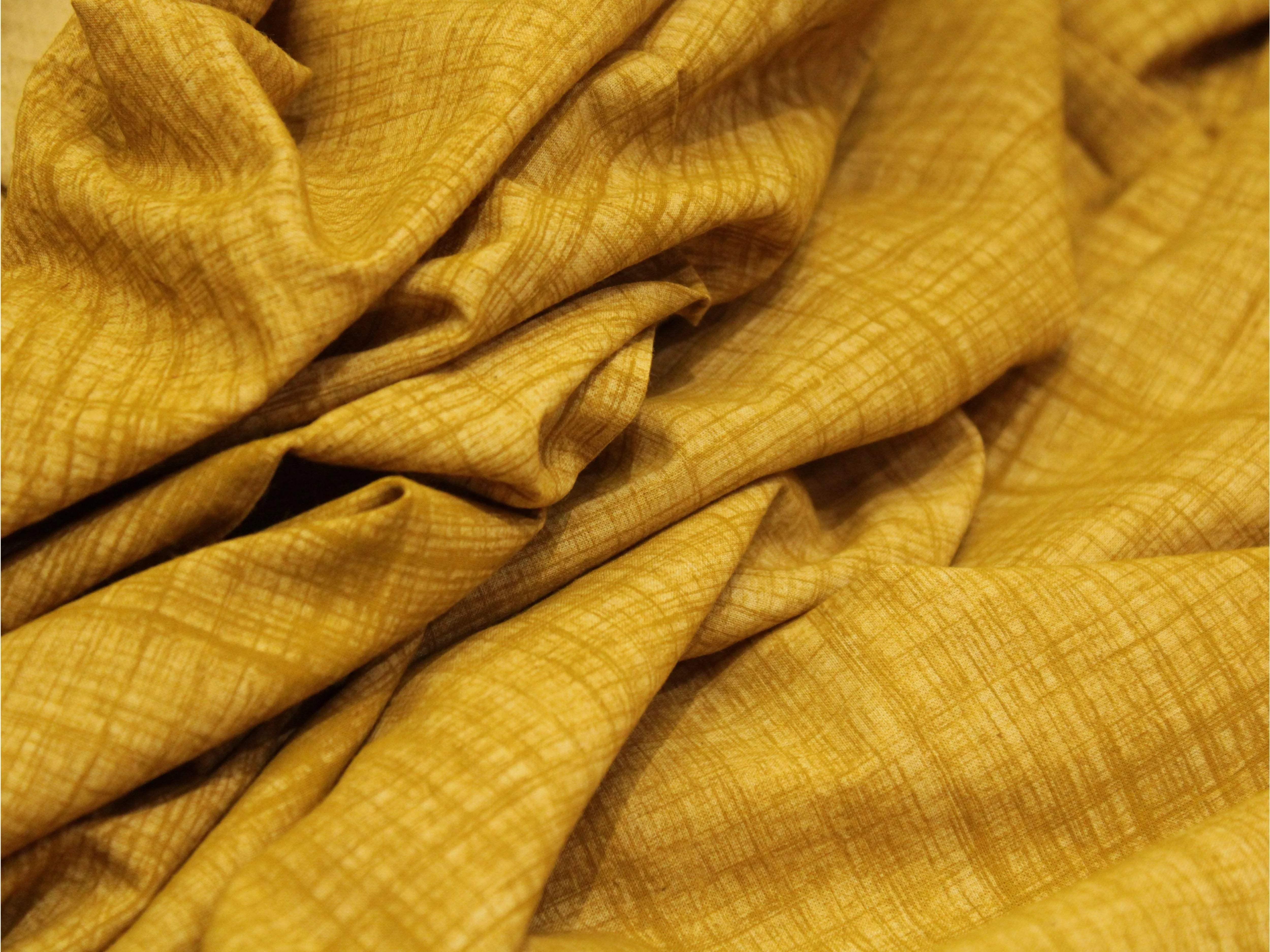 Mustard yellow cotton fabric with hand block printed textured pattern, wrinkled surface
