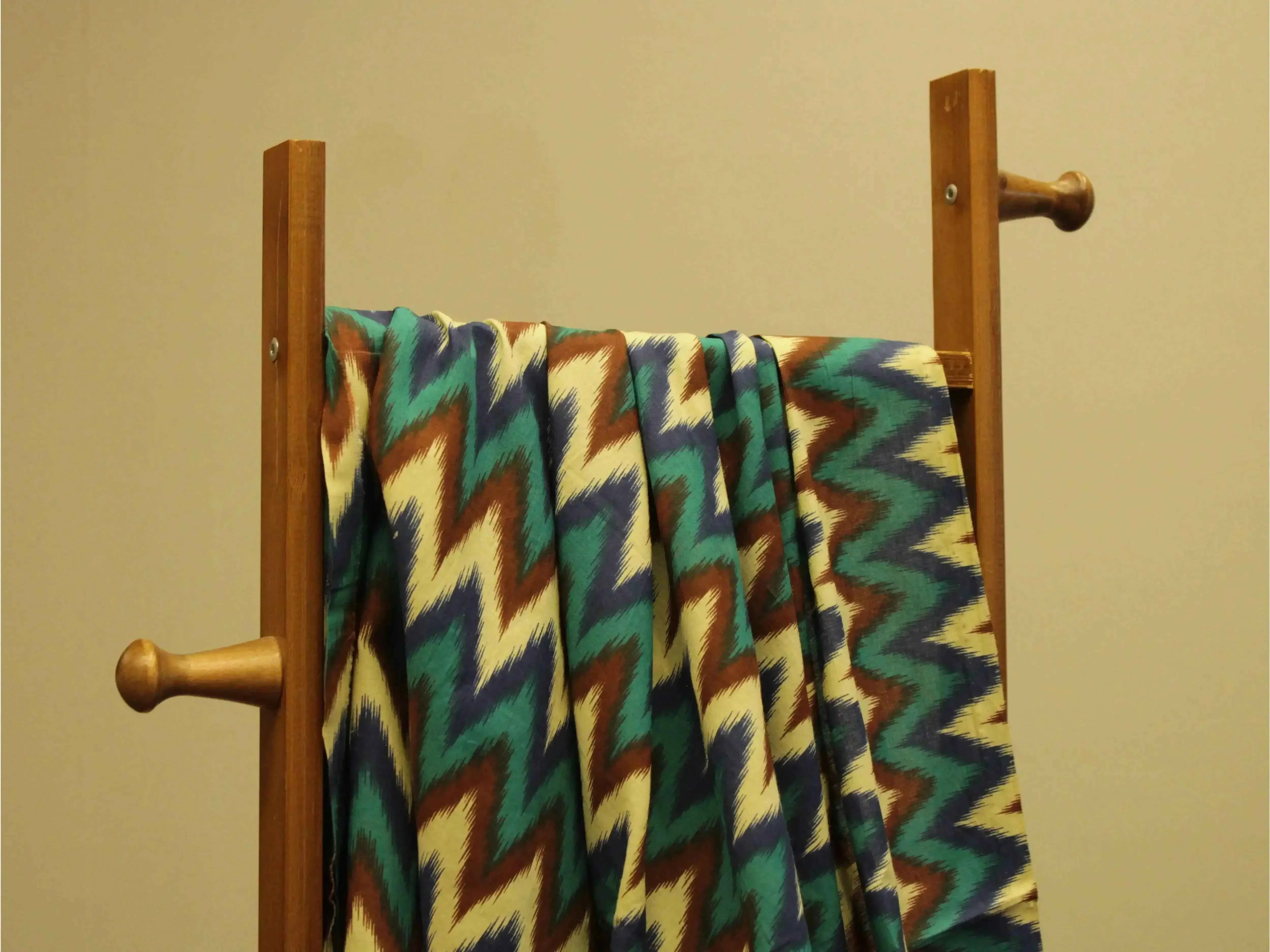 Printed cotton fabric with multicolor zigzag pattern draped on wooden rack