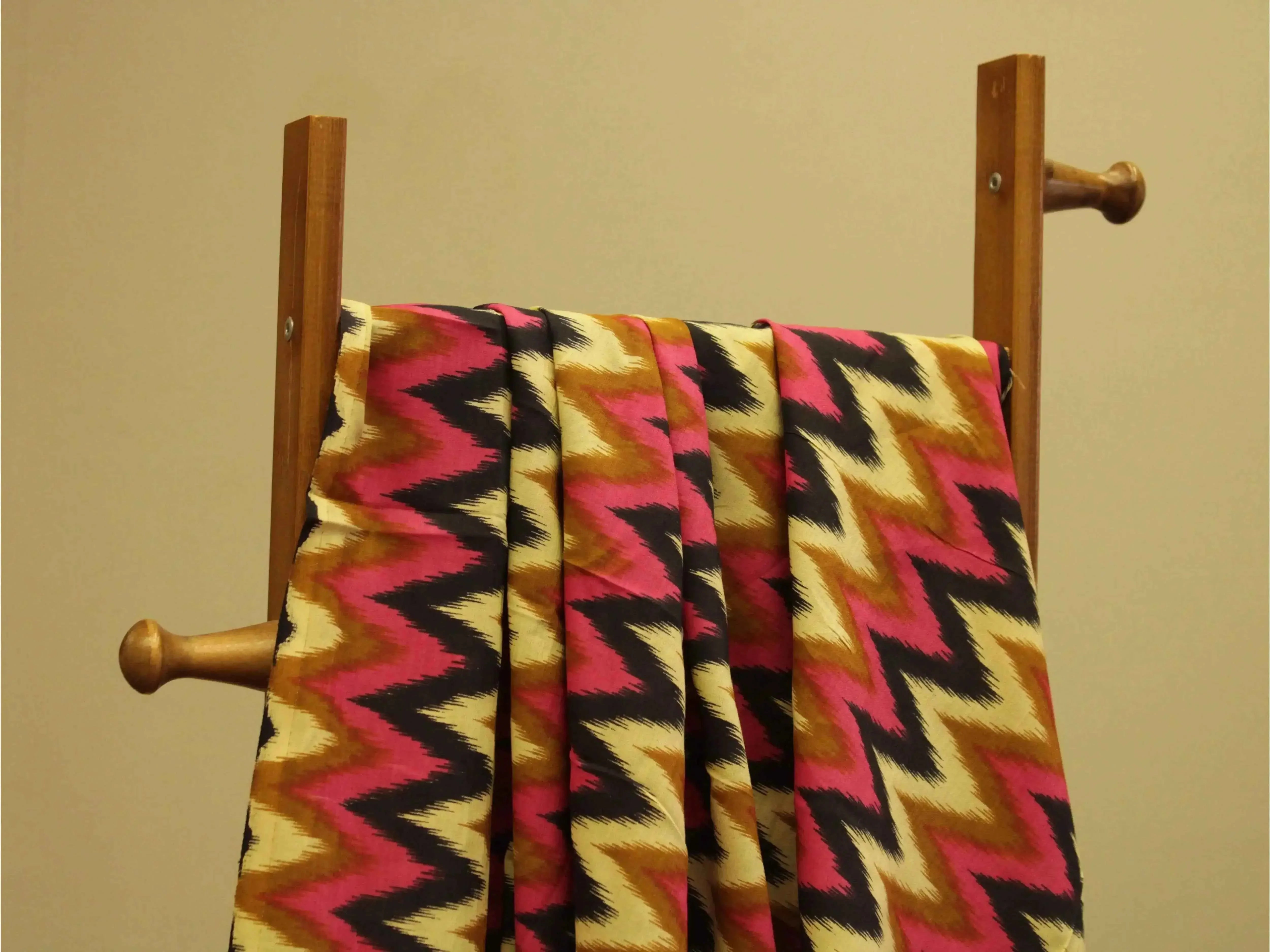 Euphoric cotton printed fabric with pink, yellow, and black zigzag pattern on a rack