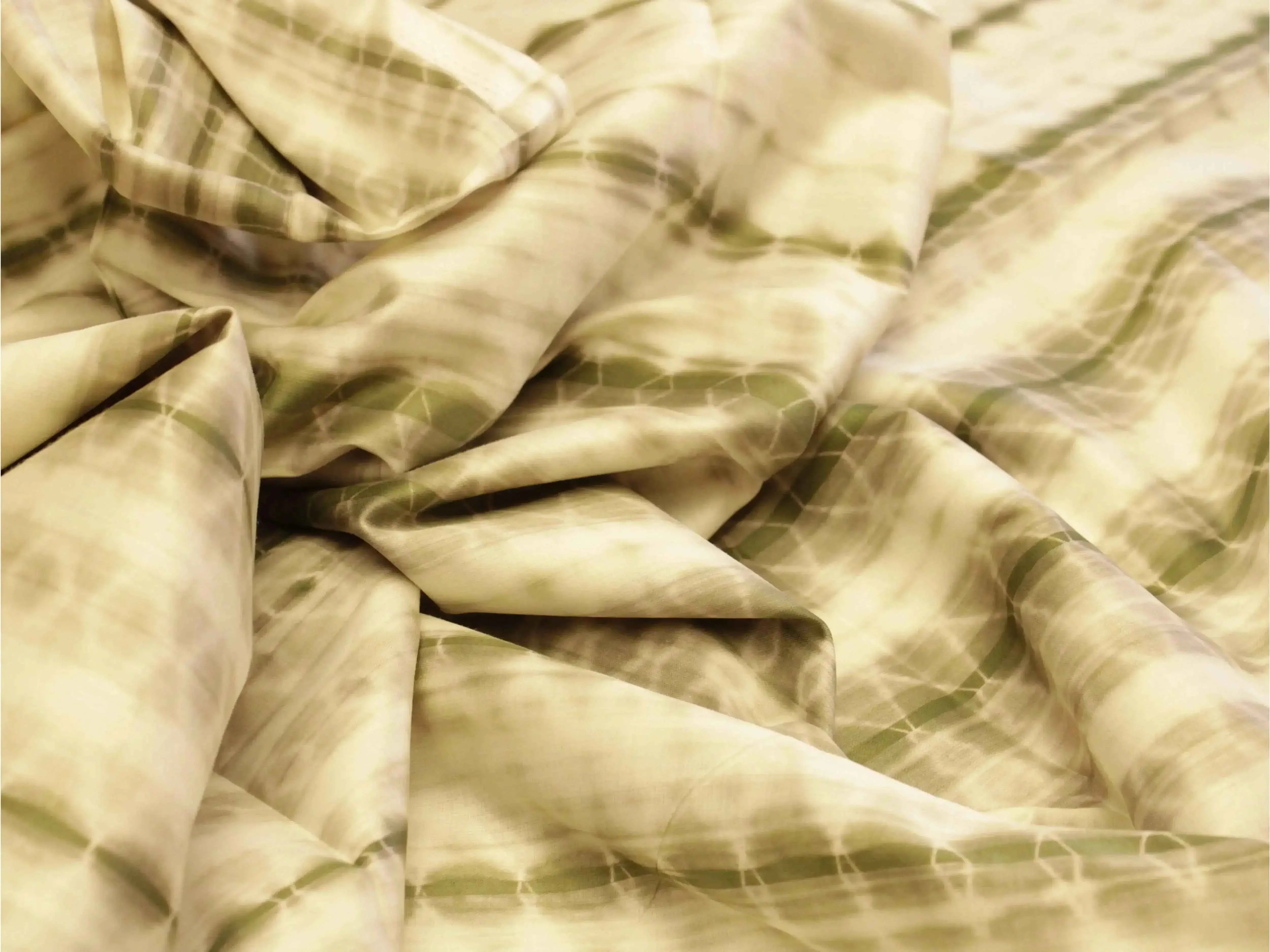 Dusty green shibori printed cotton satin fabric with abstract tie-dye pattern, close-up view
