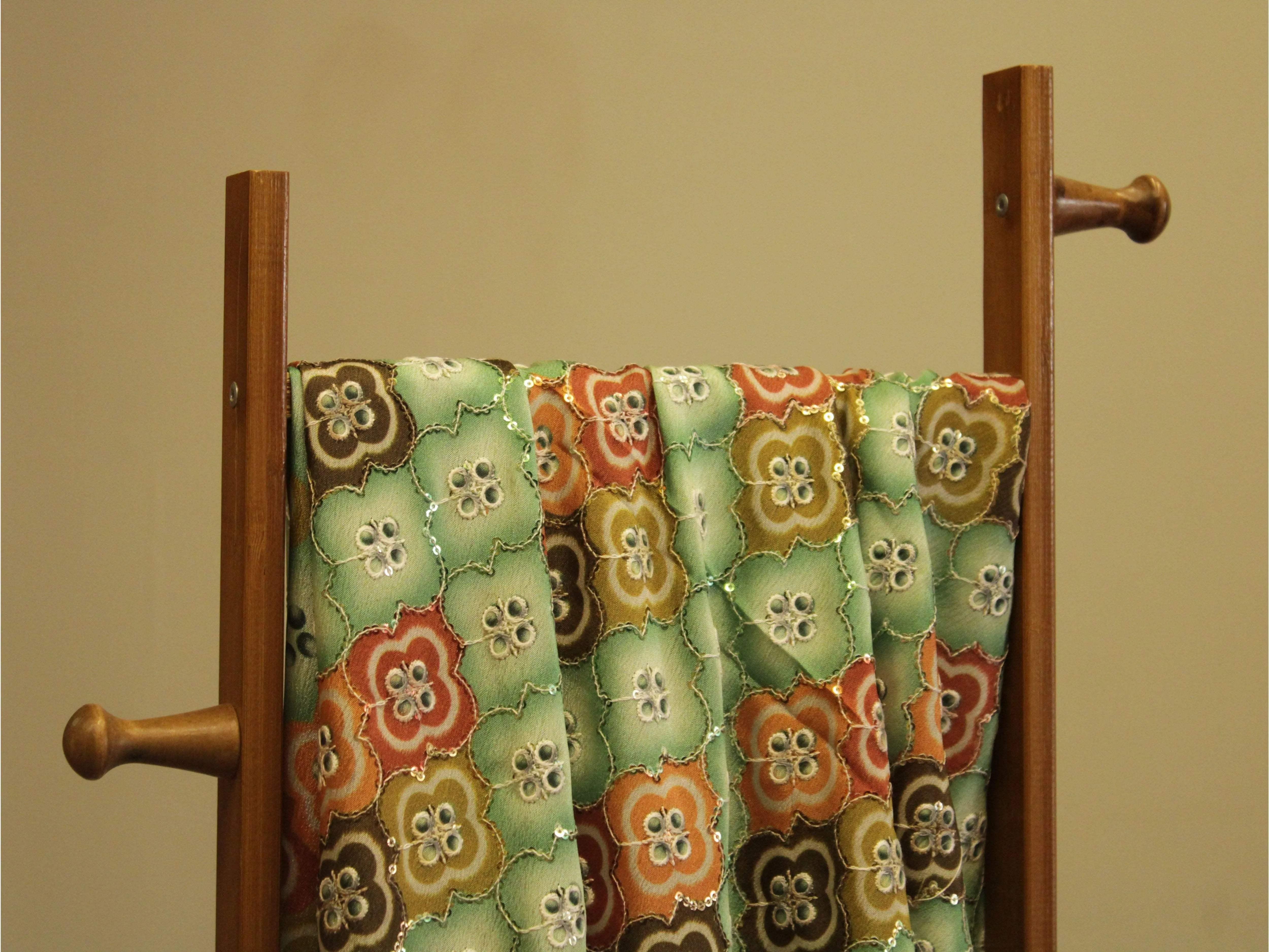 Colorful floral digital chinon silk fabric with sequin embroidery draped on a wooden stand