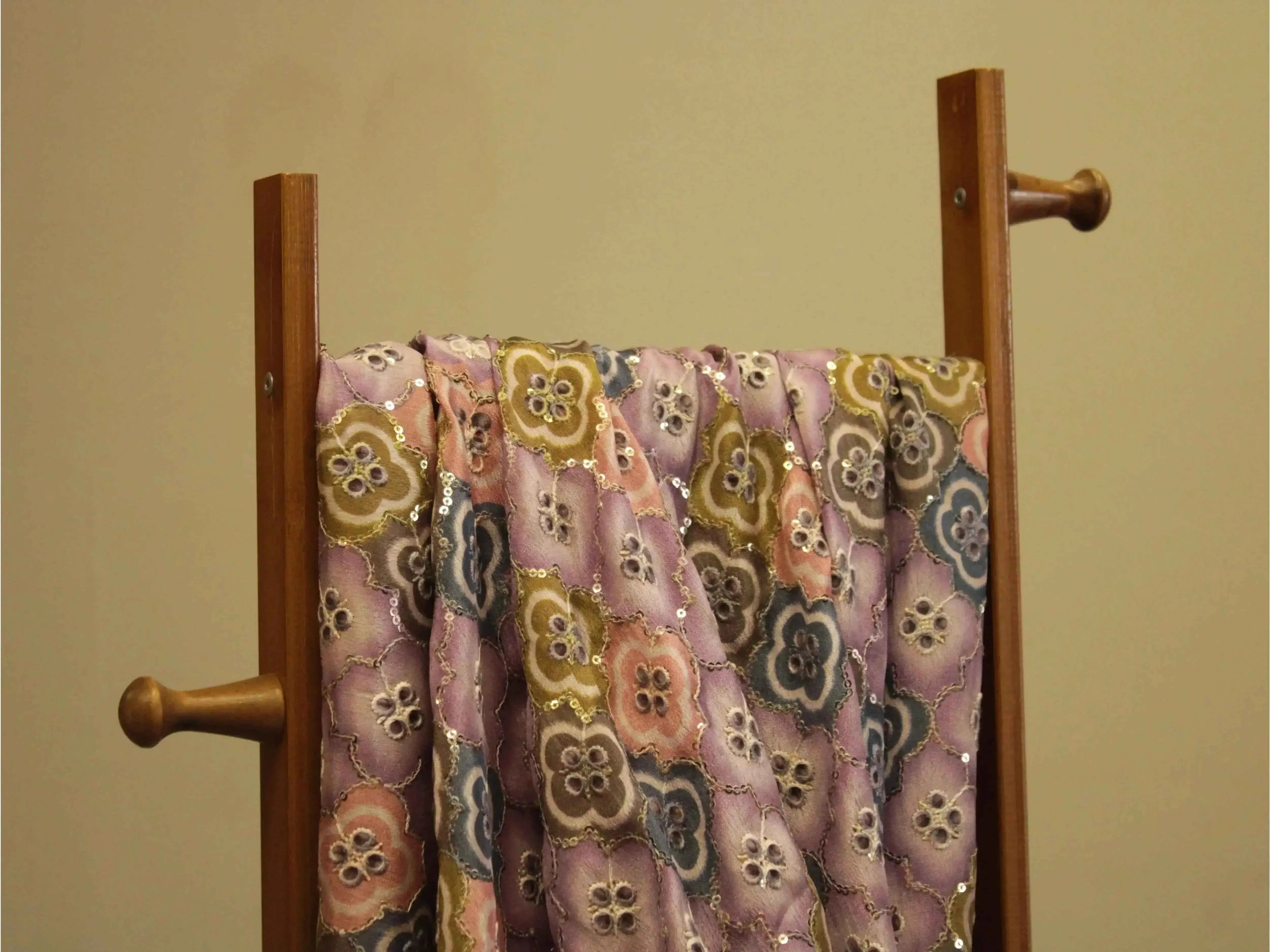 Pastel floral sequin embroidered Chinon silk fabric draped on a wooden stand