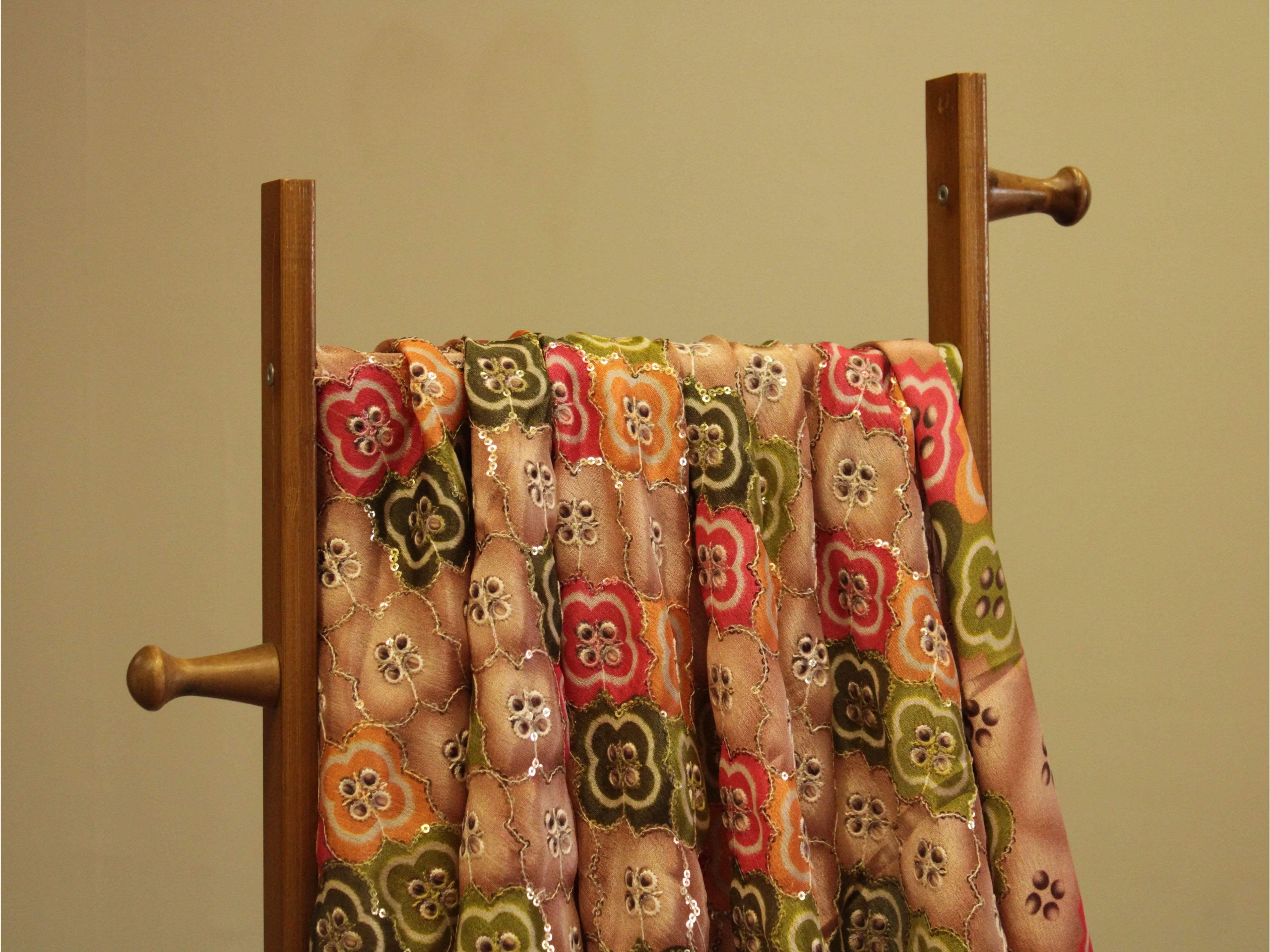 Colorful digital Chinon silk fabric with floral sequin embroidery draped on a wooden rack
