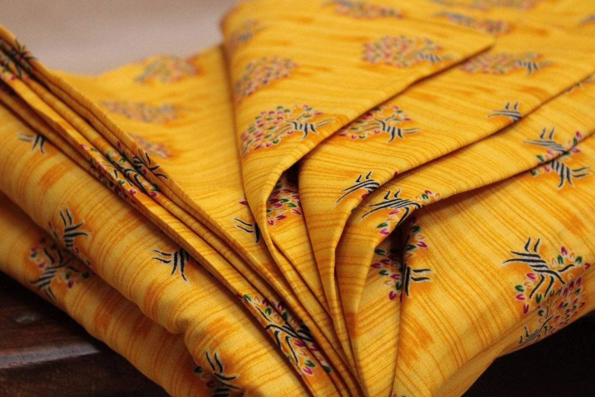 Yellow cotton buti screen print fabric with floral patterns, folded neatly