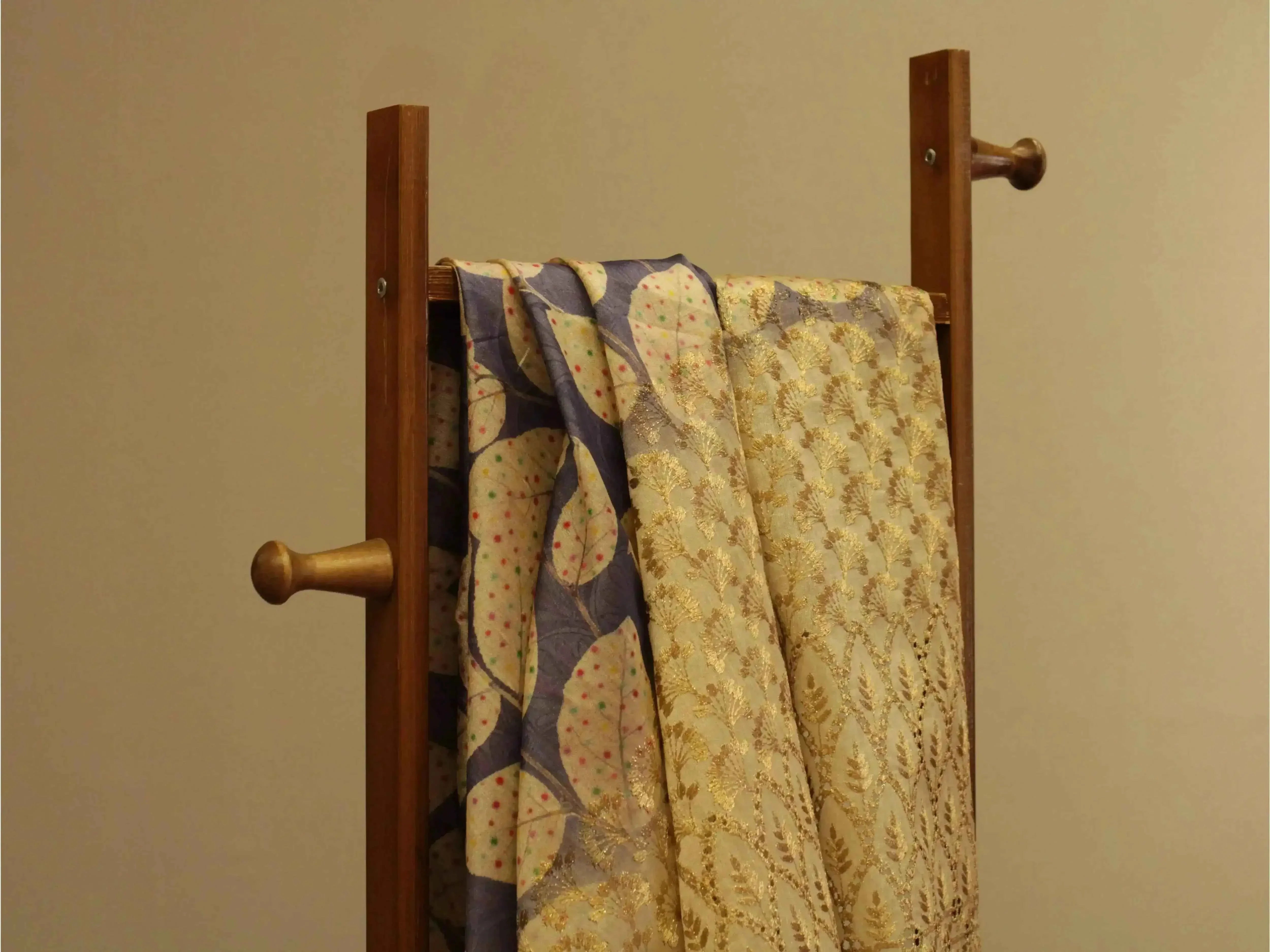 Fine silk digital print fabric with gold panel work draped over a wooden stand