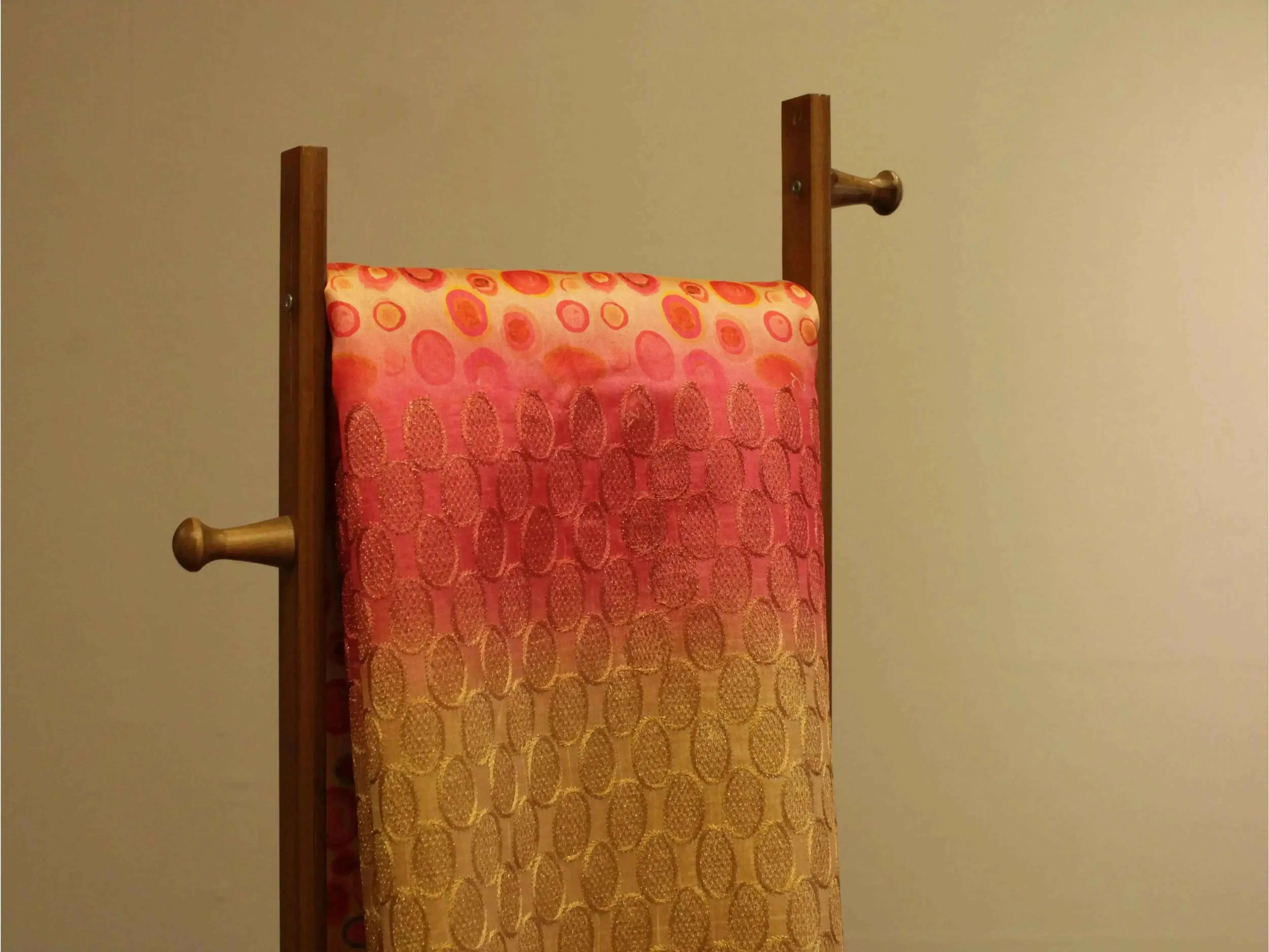 Fine silk fabric with pink and gold digital print, draped on wooden stand