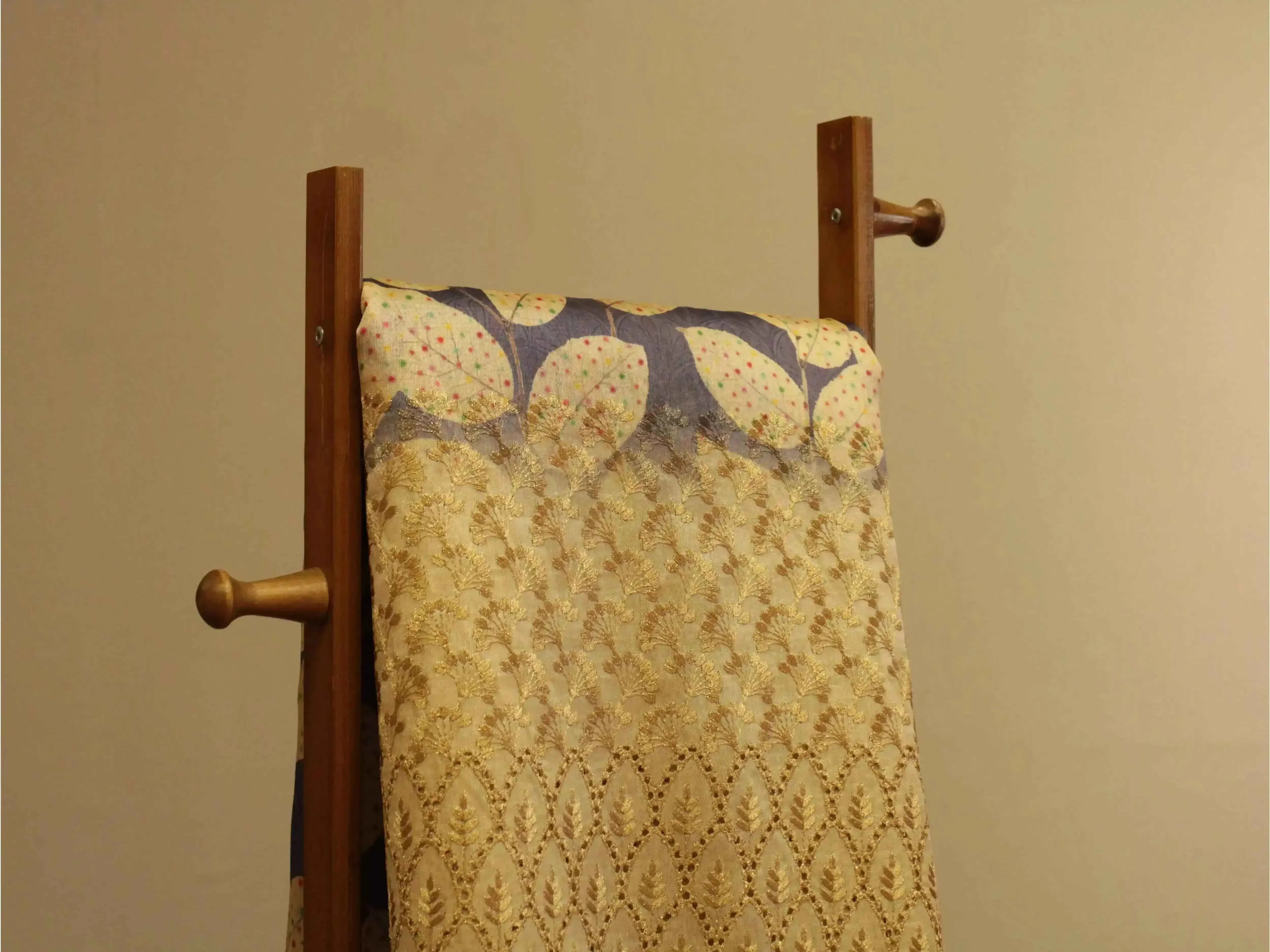 Fine silk fabric with gold floral embroidery and digital print panel, draped on a wooden stand