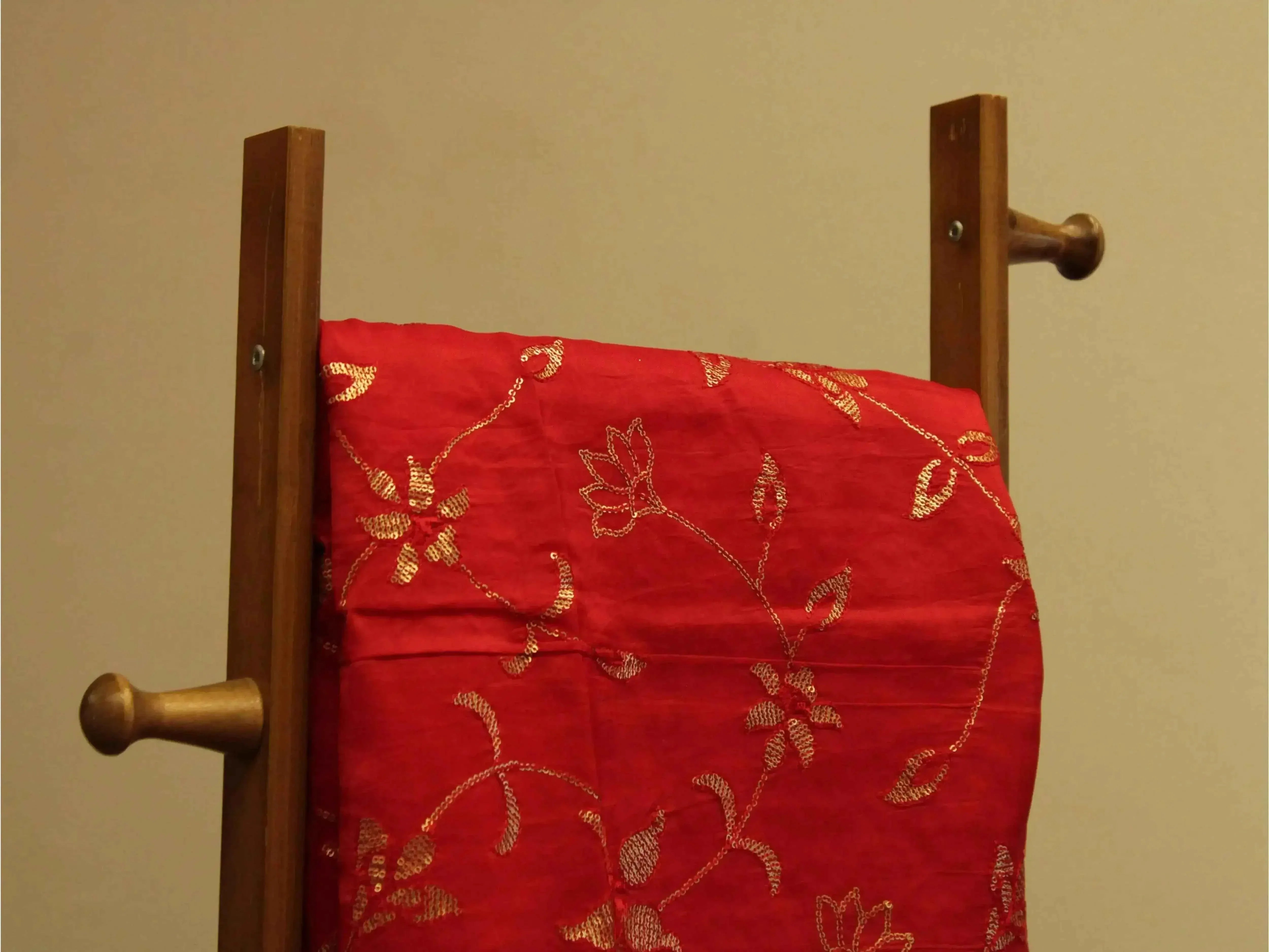 Red Uppada silk fabric with micro sequin jaal embroidery draped on a wooden stand