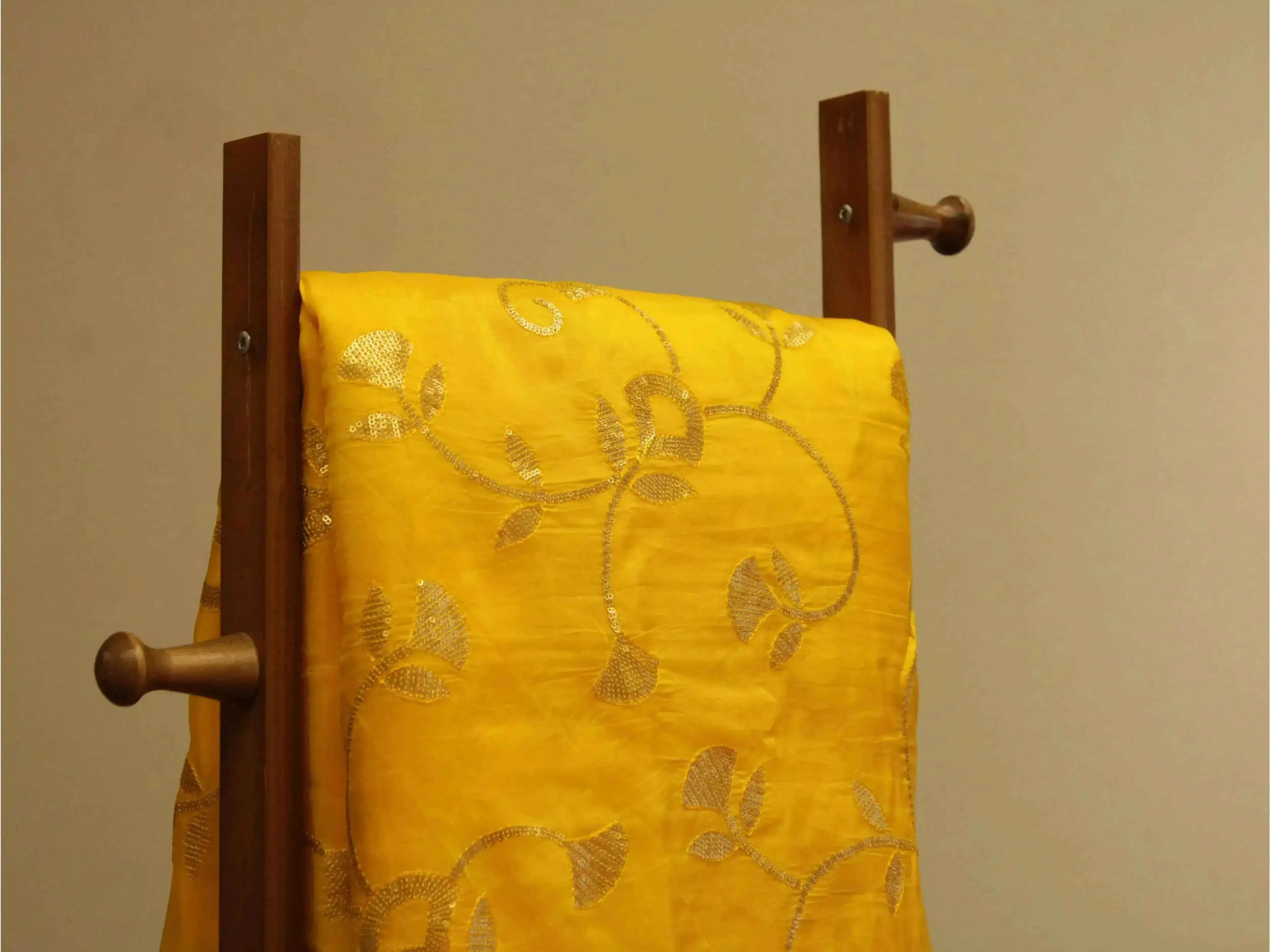 Yellow Uppada silk fabric with gold sequin jaal work draped on wooden stand