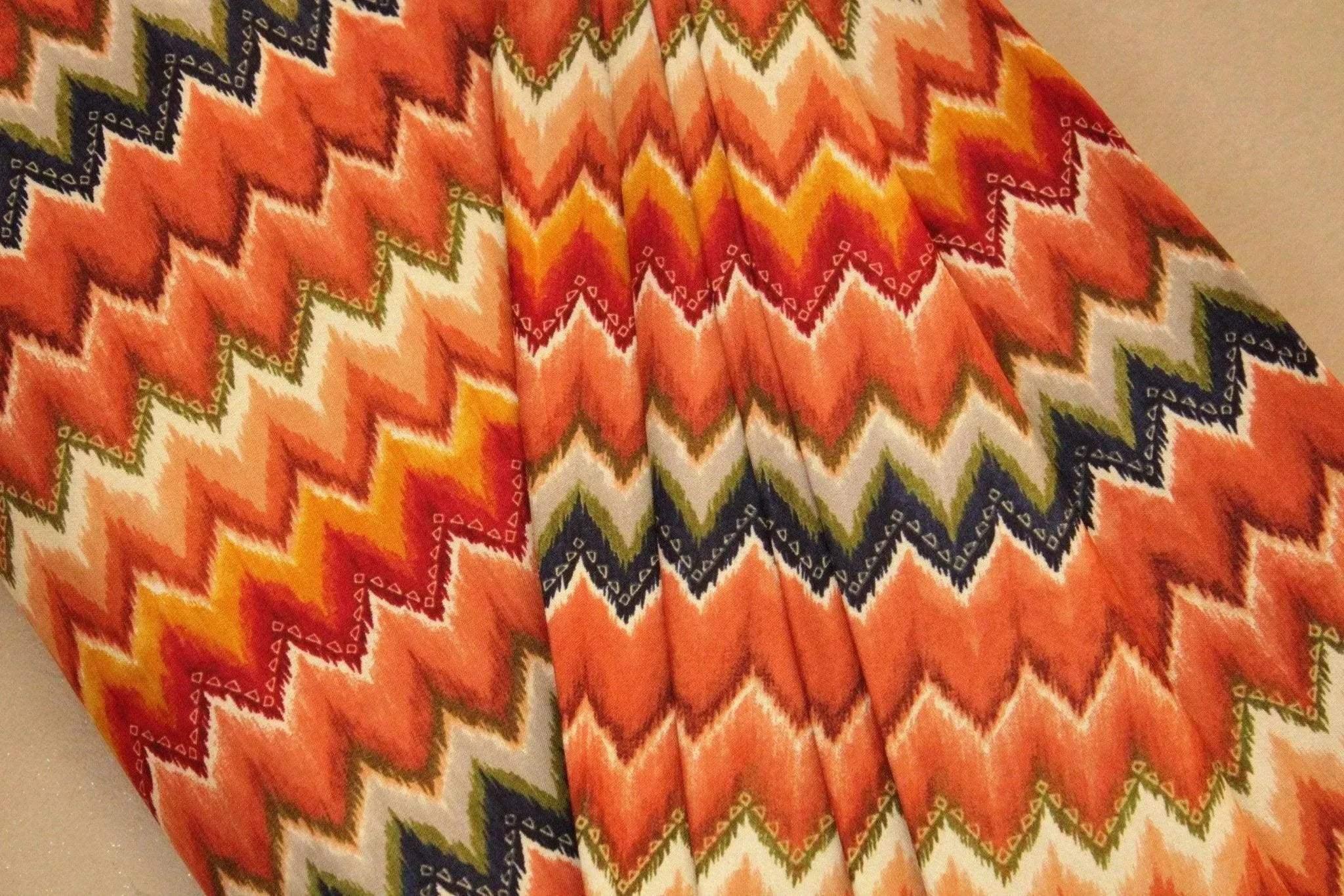 Amber Italian rayon fabric with multicolor zigzag chevron pattern, draped on surface