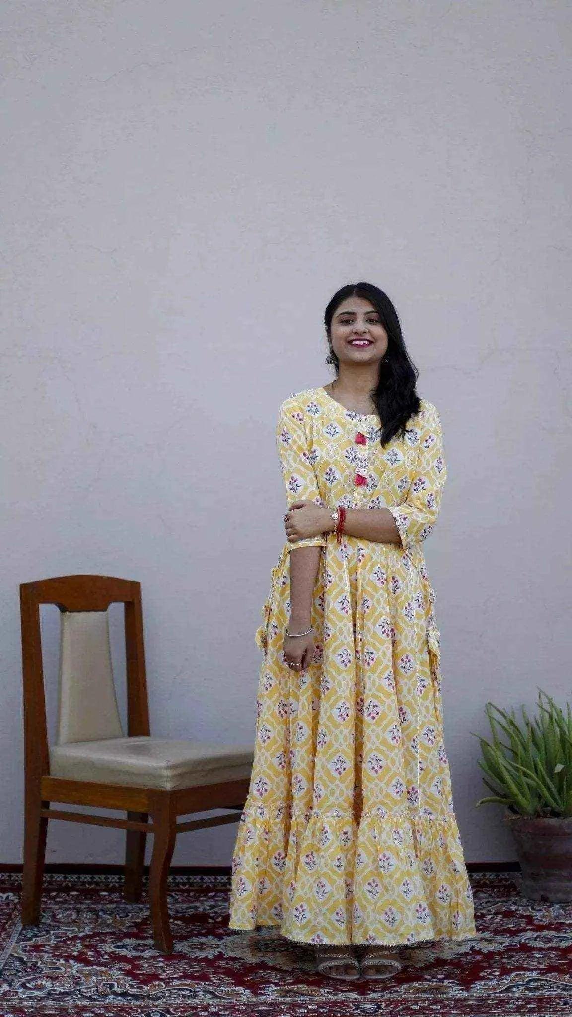 Woman in yellow printed mulmul cotton gown with three-quarter sleeves, indoor setting