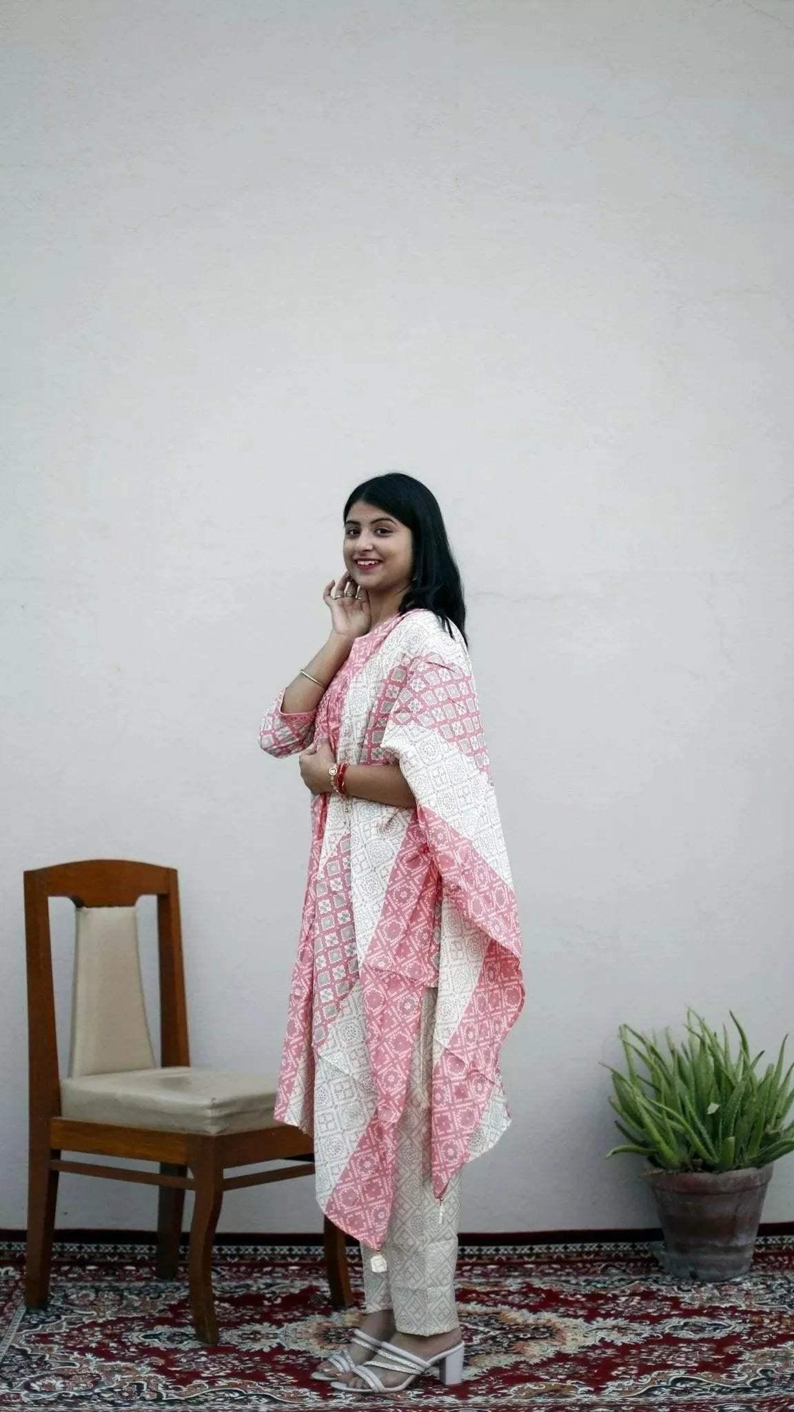 Woman in a cream and pink printed muslin ethnic suit set with dupatta and pants, standing indoors