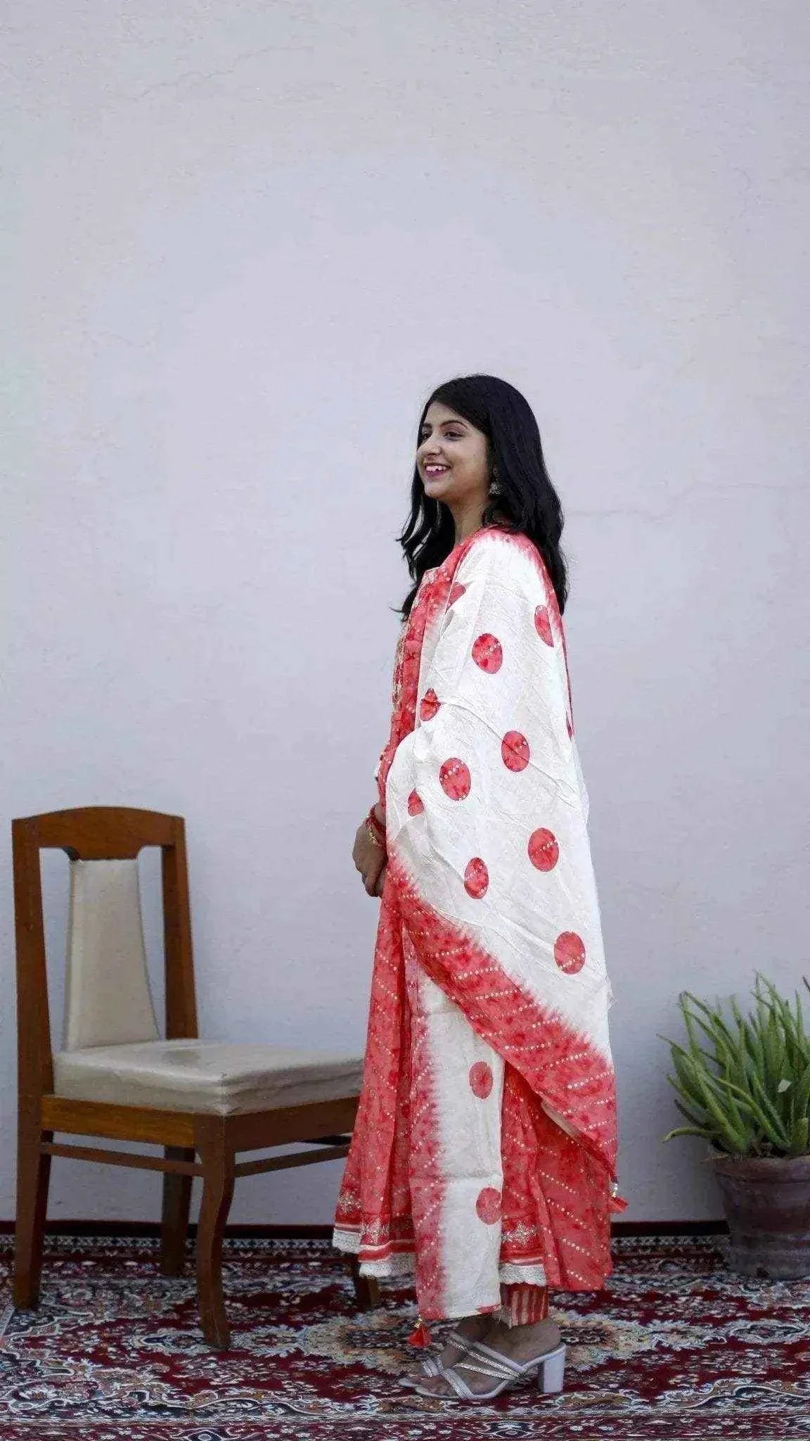 Woman in peach and white muslin silk anarkali kurta set with dupatta and pants, standing indoors