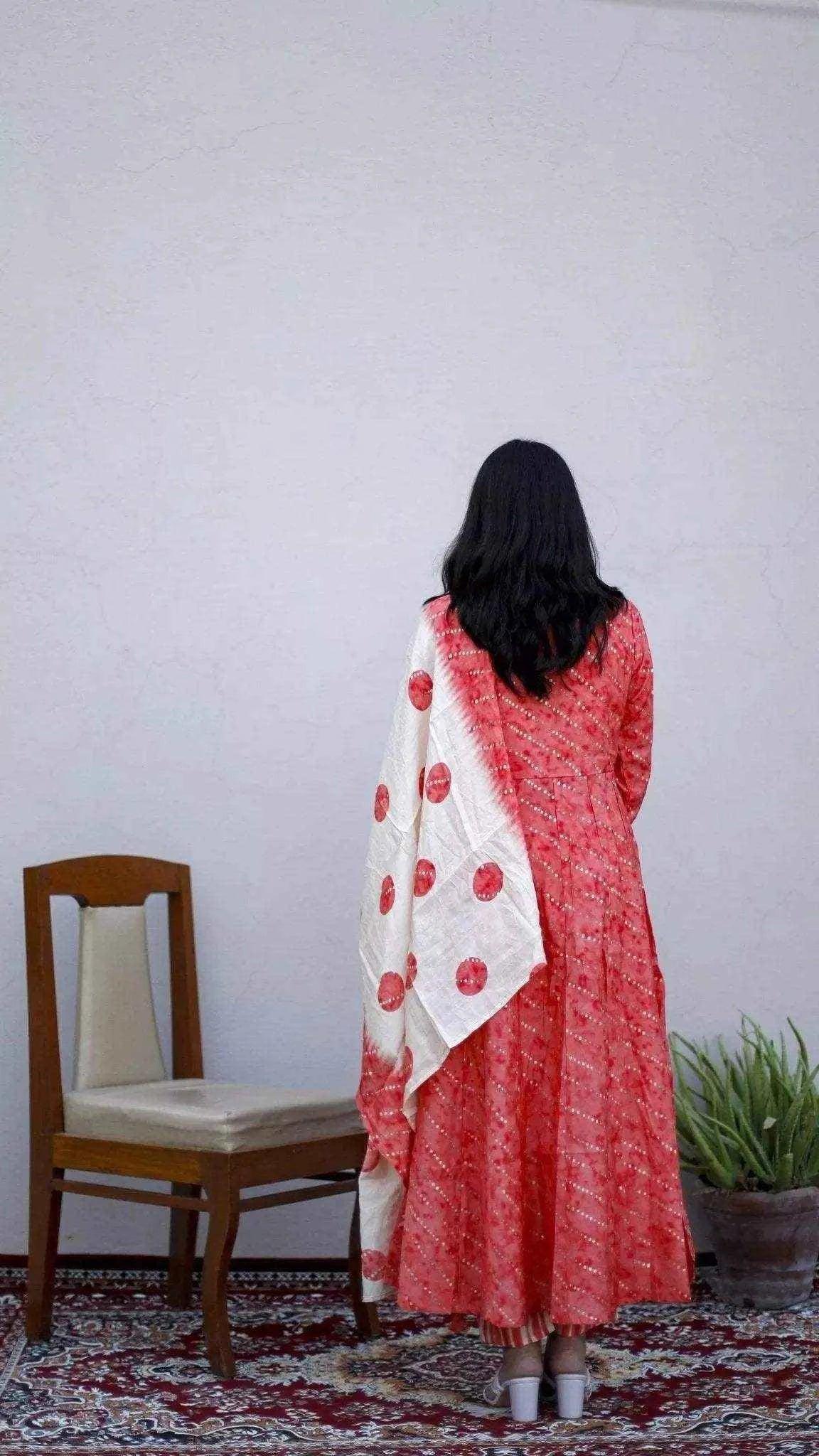 Woman wearing a red muslin silk Anarkali kurta with dupatta and pants, standing indoors