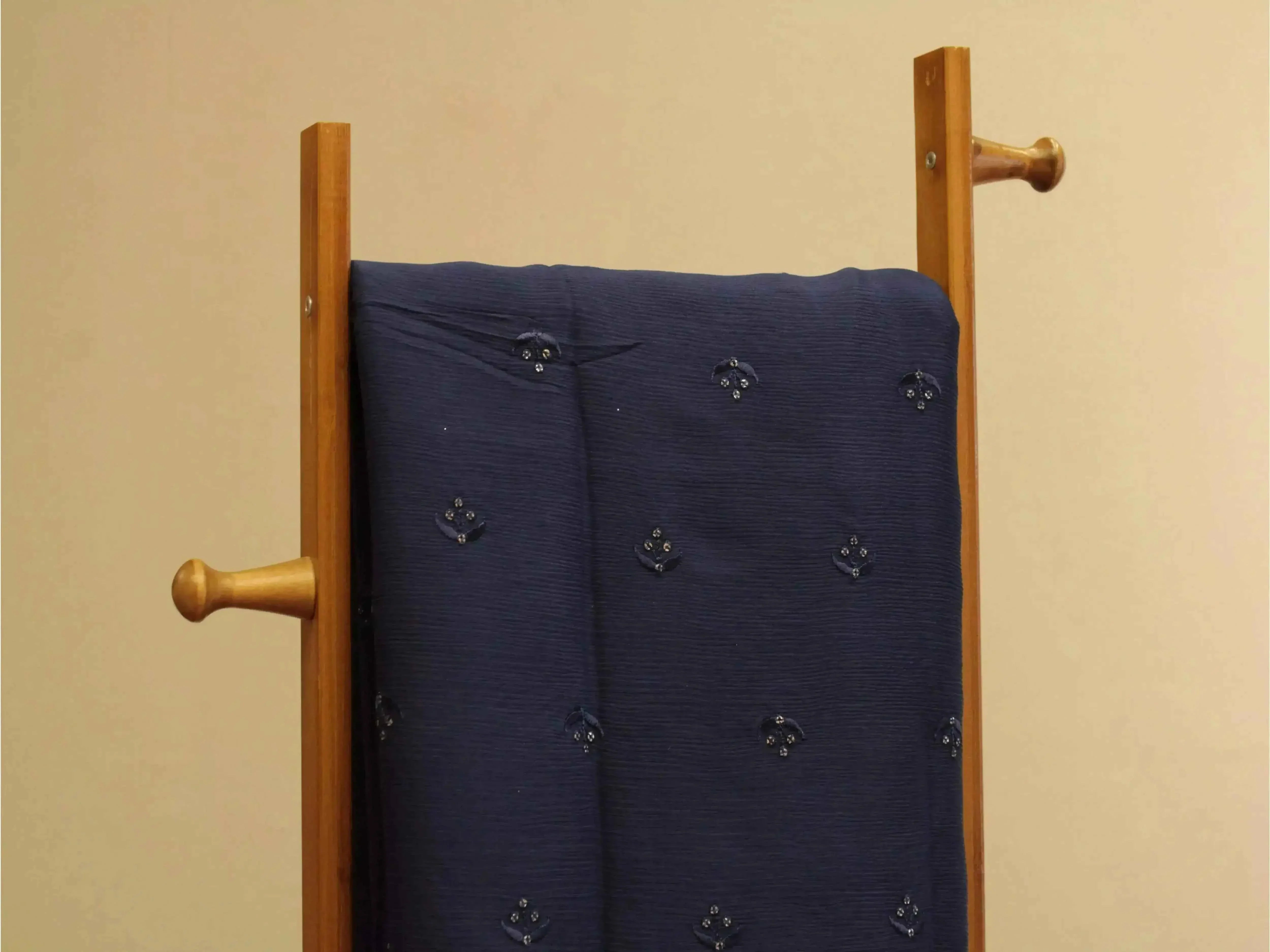 Pure blue chinon fabric with minimal buti embroidery draped on wooden rack