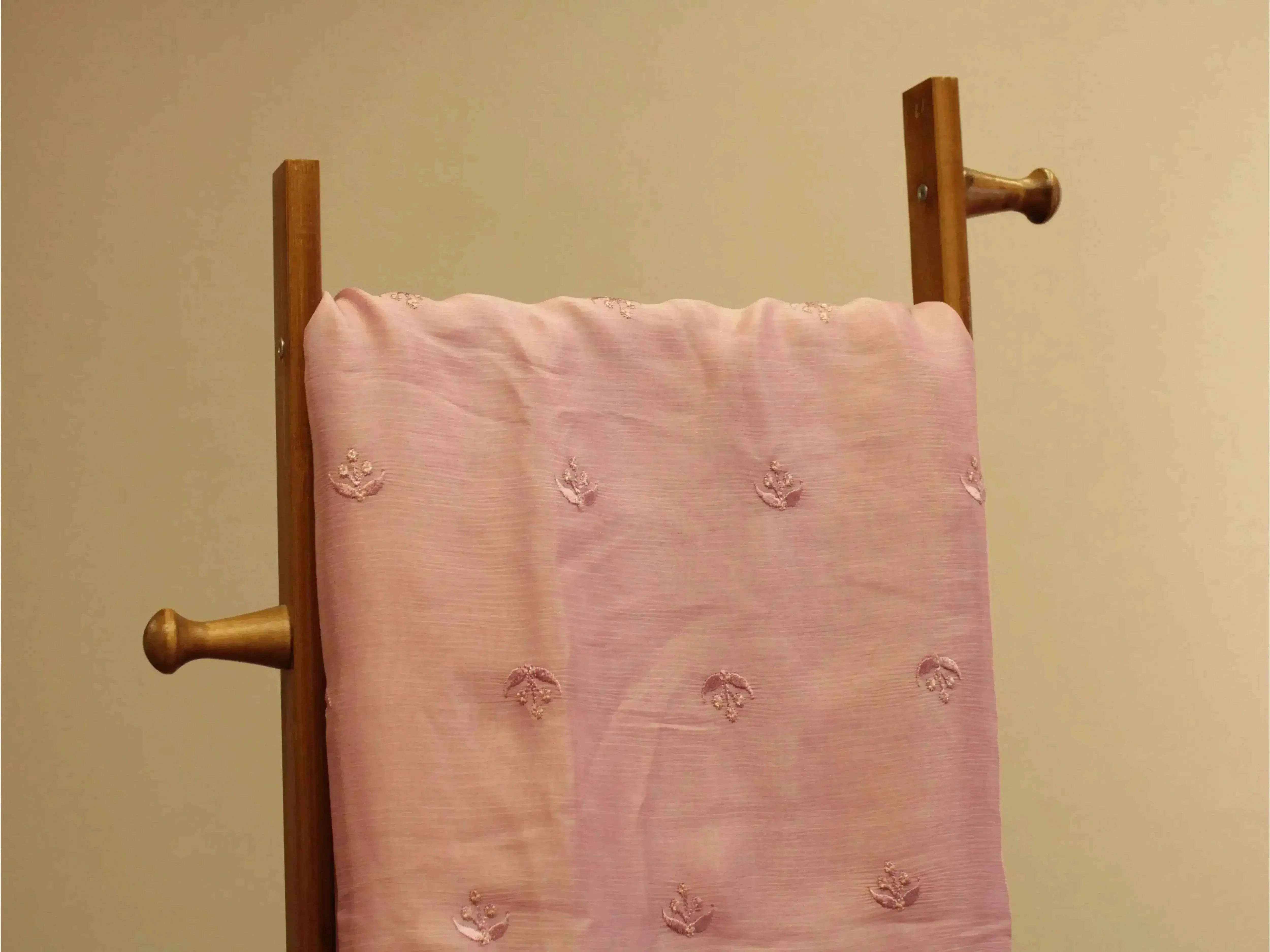 Lavender pink pure Chinon fabric with minimal buti embroidery draped on a wooden stand