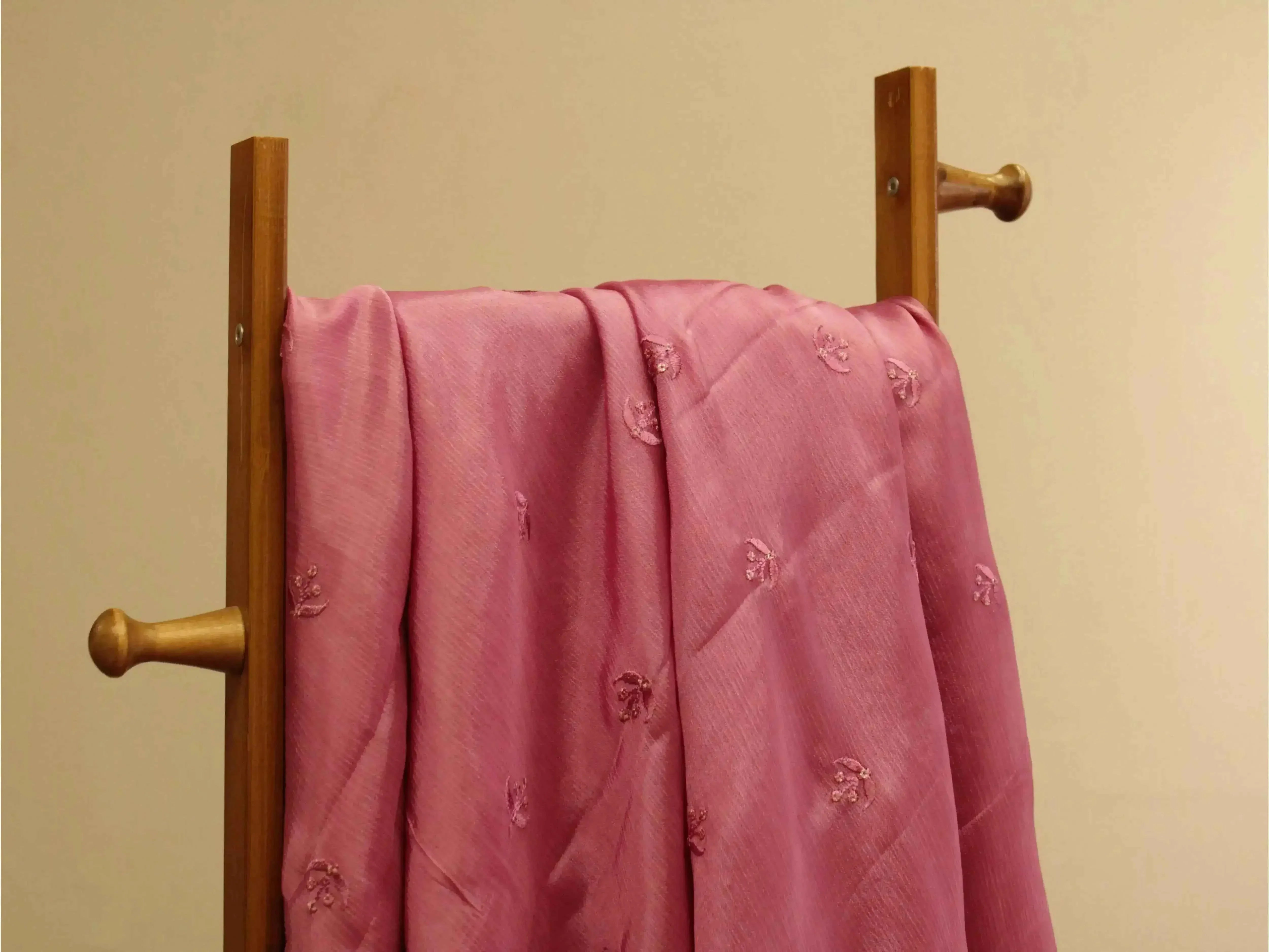Onion pink Chinon fabric with minimal buti embroidery draped on a wooden stand