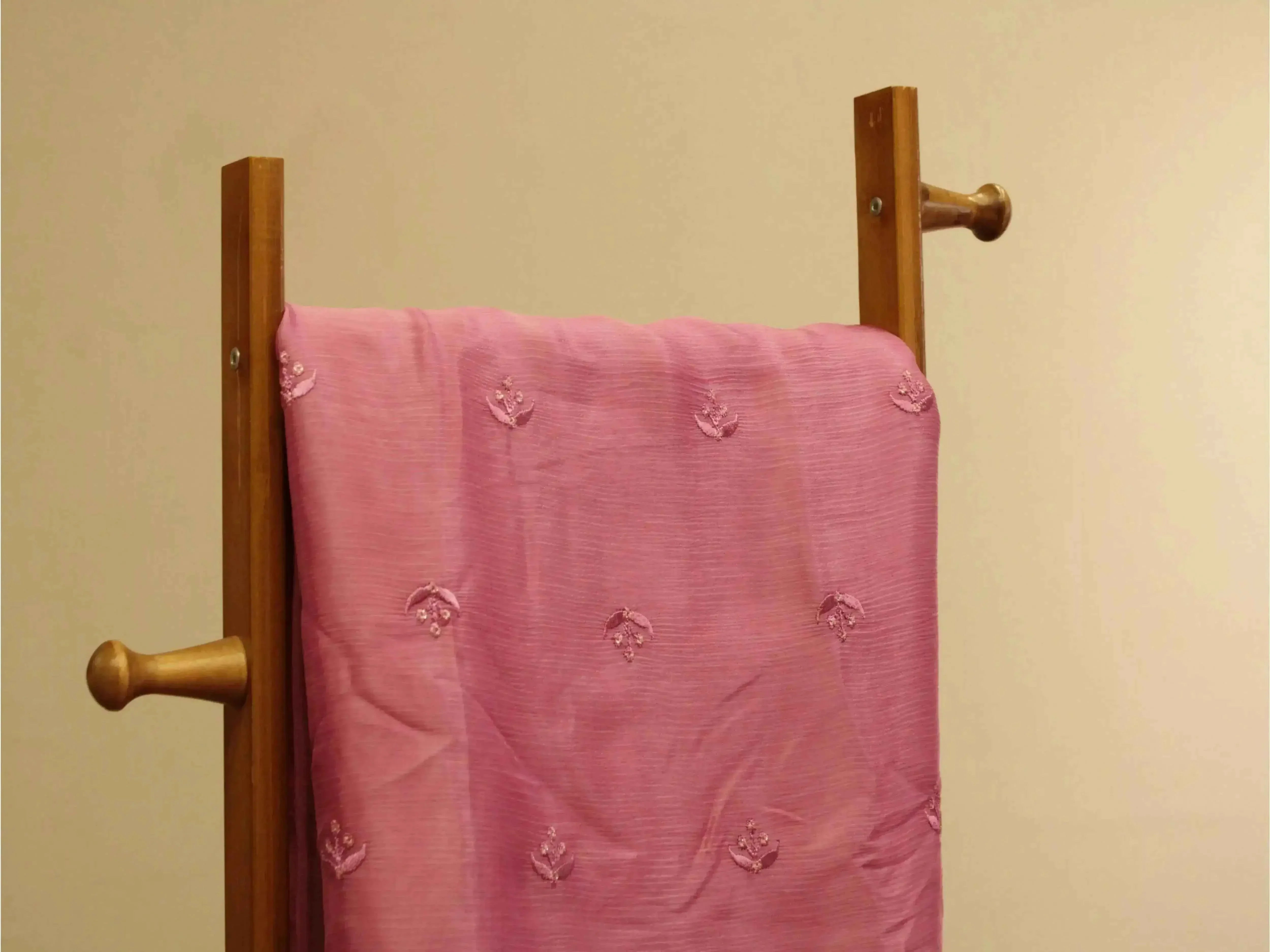 Onion pink pure Chinon fabric with minimal buti embroidery draped on a wooden stand