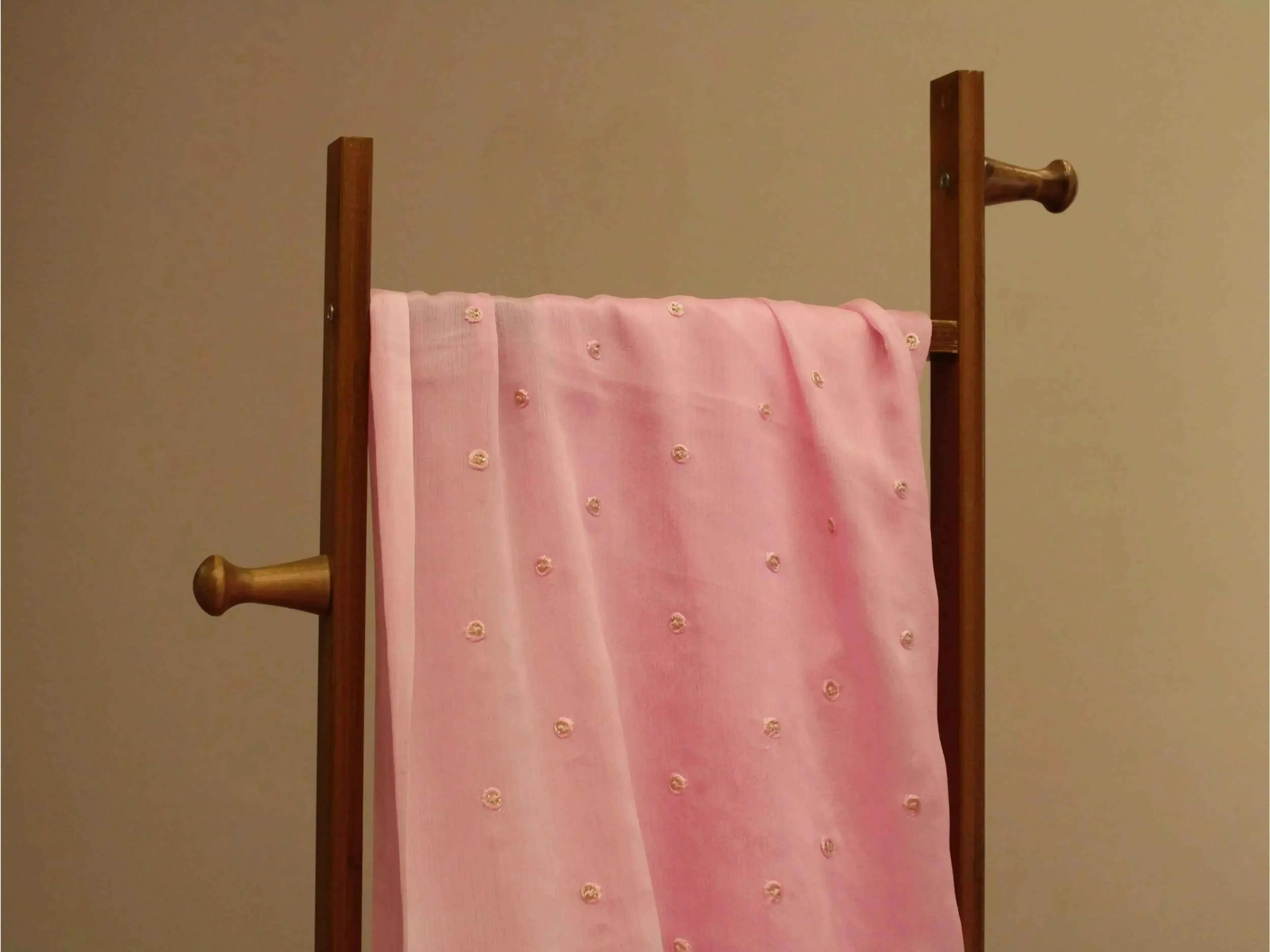 Pure chinon pink fabric with minimal buti embroidery, draped on a wooden stand