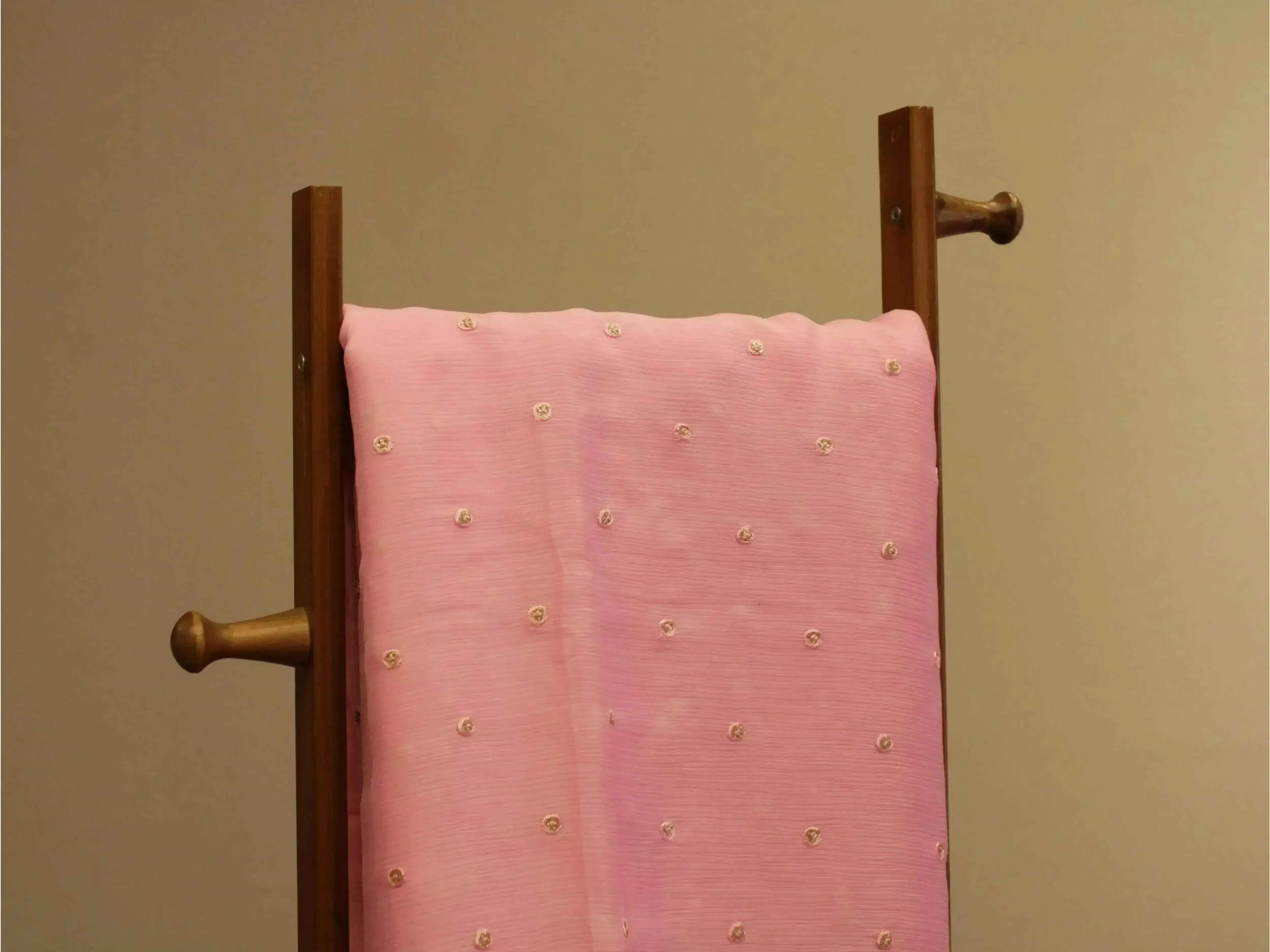 Pure chinon pink fabric with minimal buti embroidery draped over wooden stand