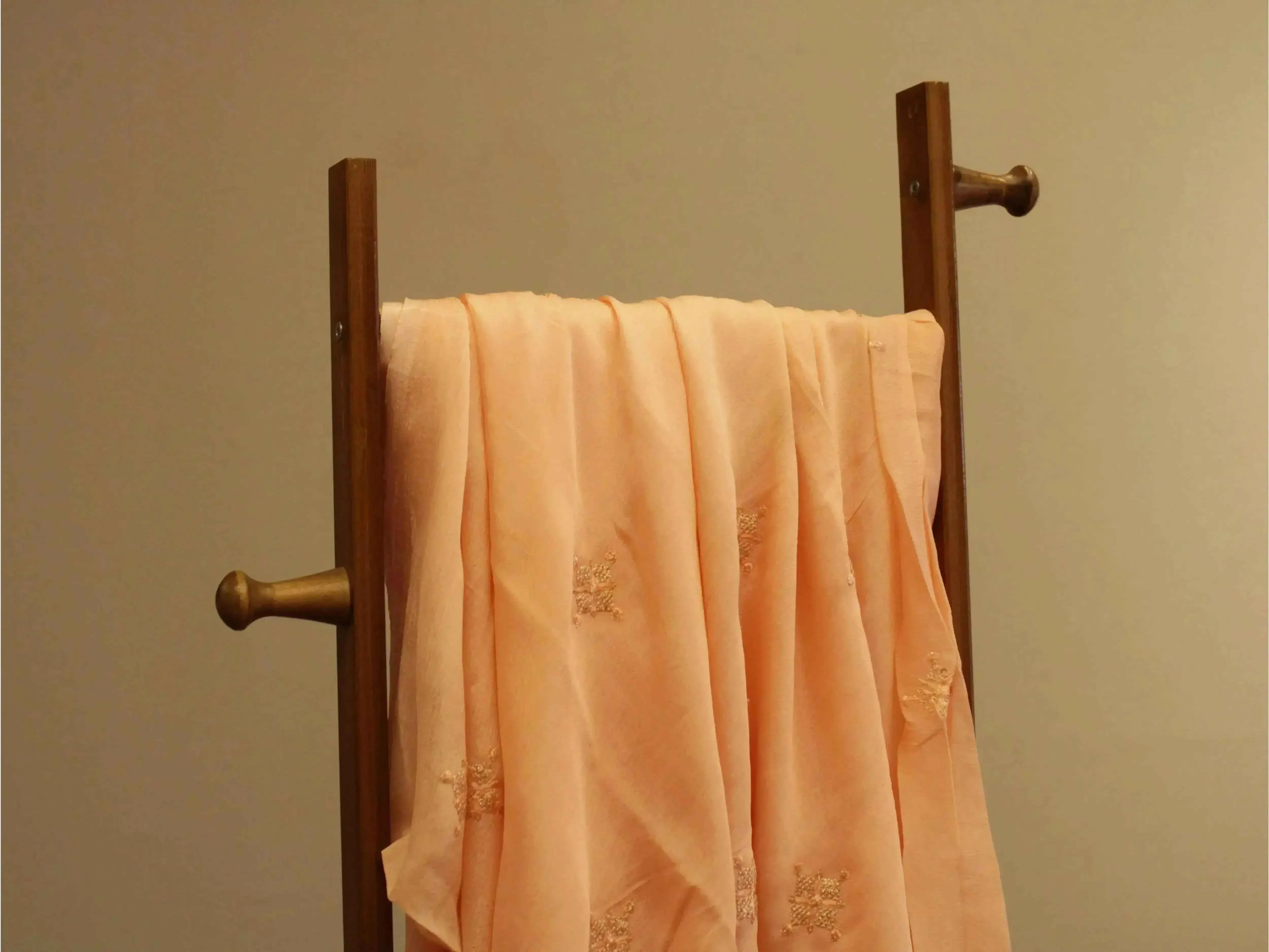 Pure Chinon minimal buti work fabric in peach draped on wooden stand