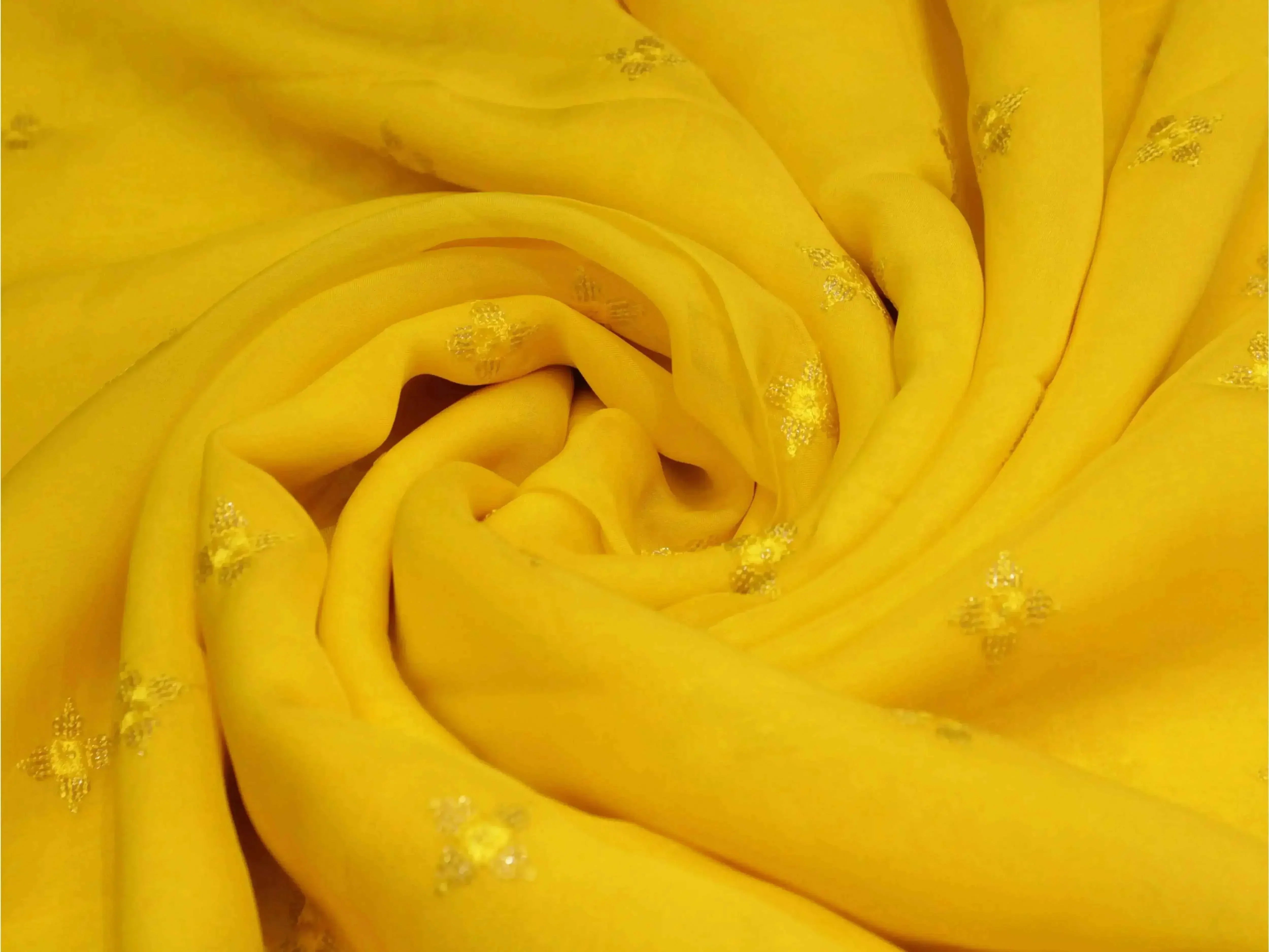 Pure yellow chinon fabric with minimal buti embroidery, soft texture, folded view