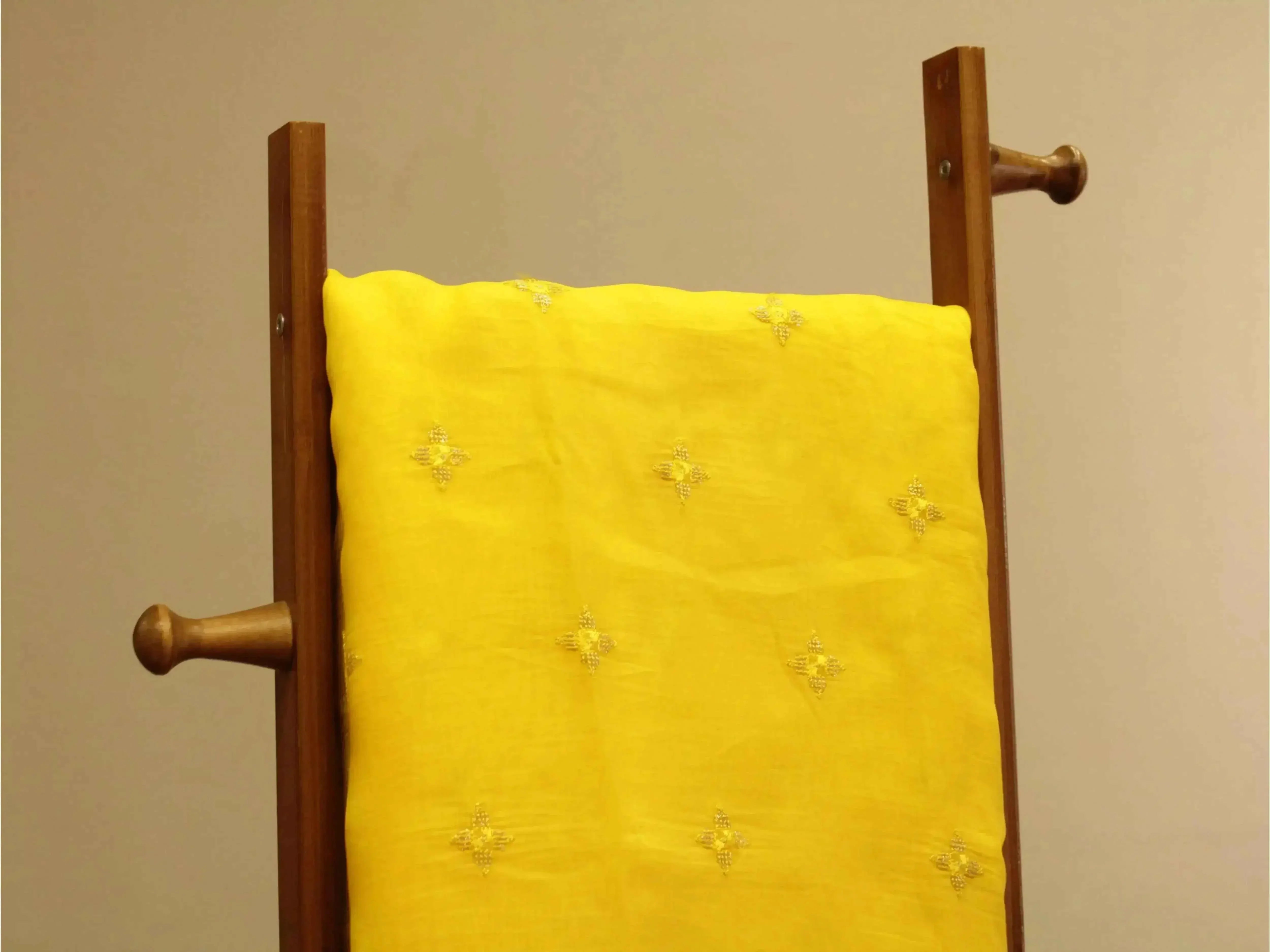 Pure chinon yellow fabric with minimal buti embroidery, displayed on wooden stand