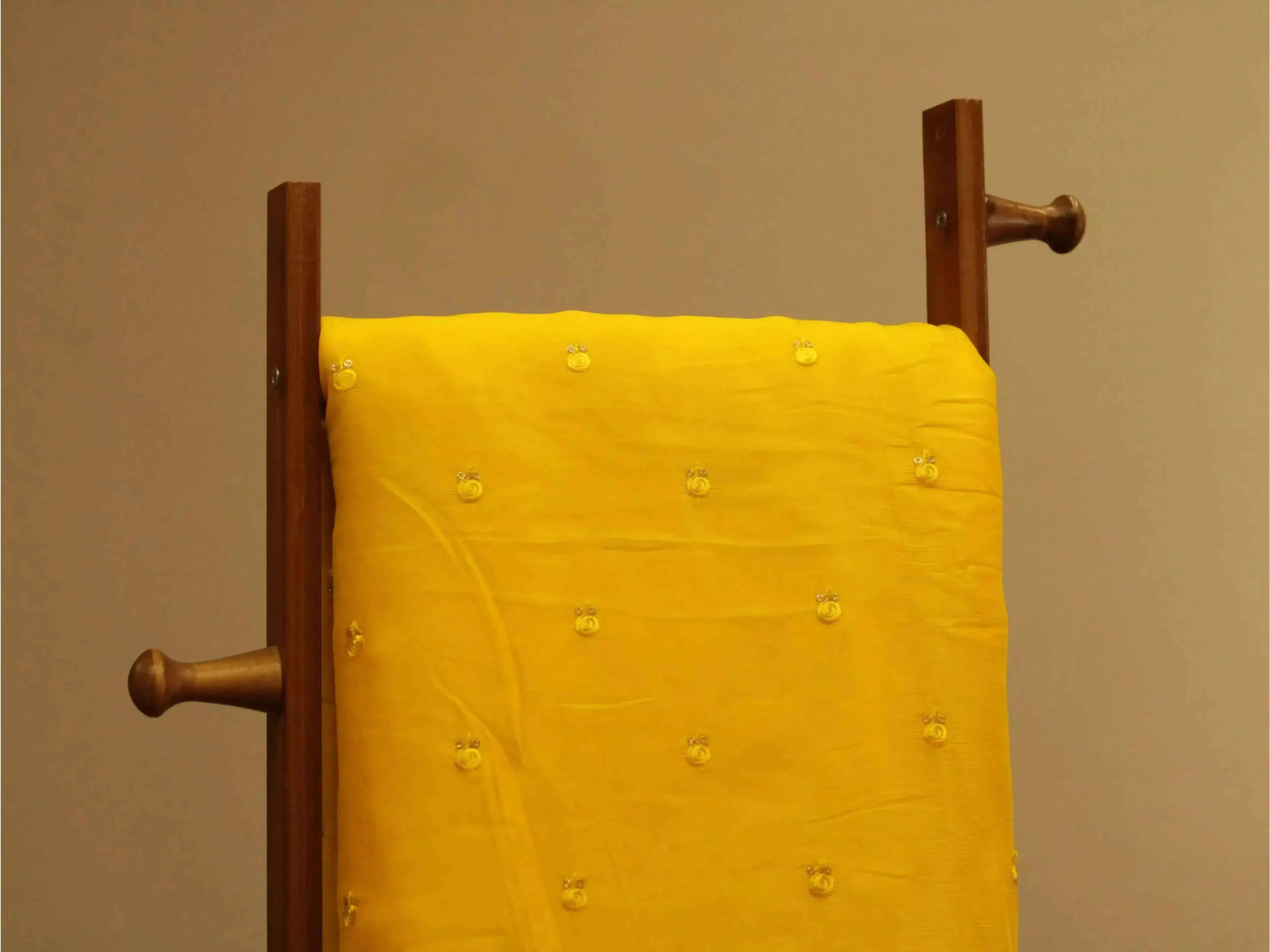 Pure chinon yellow fabric with minimal buti work, draped on a wooden stand