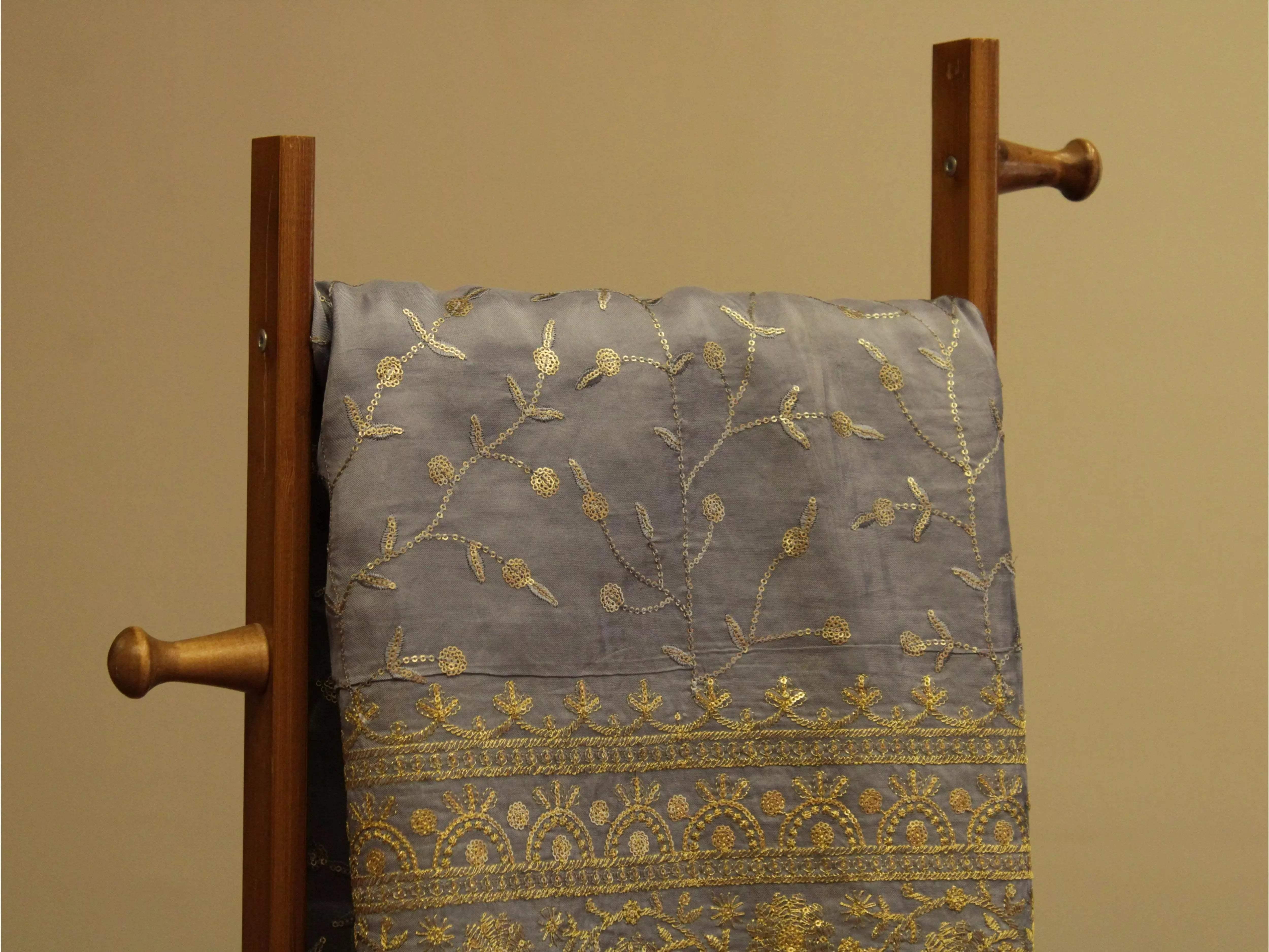 Grey upada silk fabric with intricate gold micro work and panel pattern draped on wooden stand