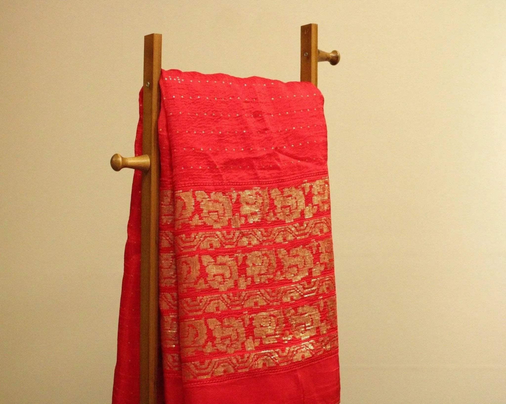 Red Upada silk fabric with gold floral micro work, draped on a wooden stand