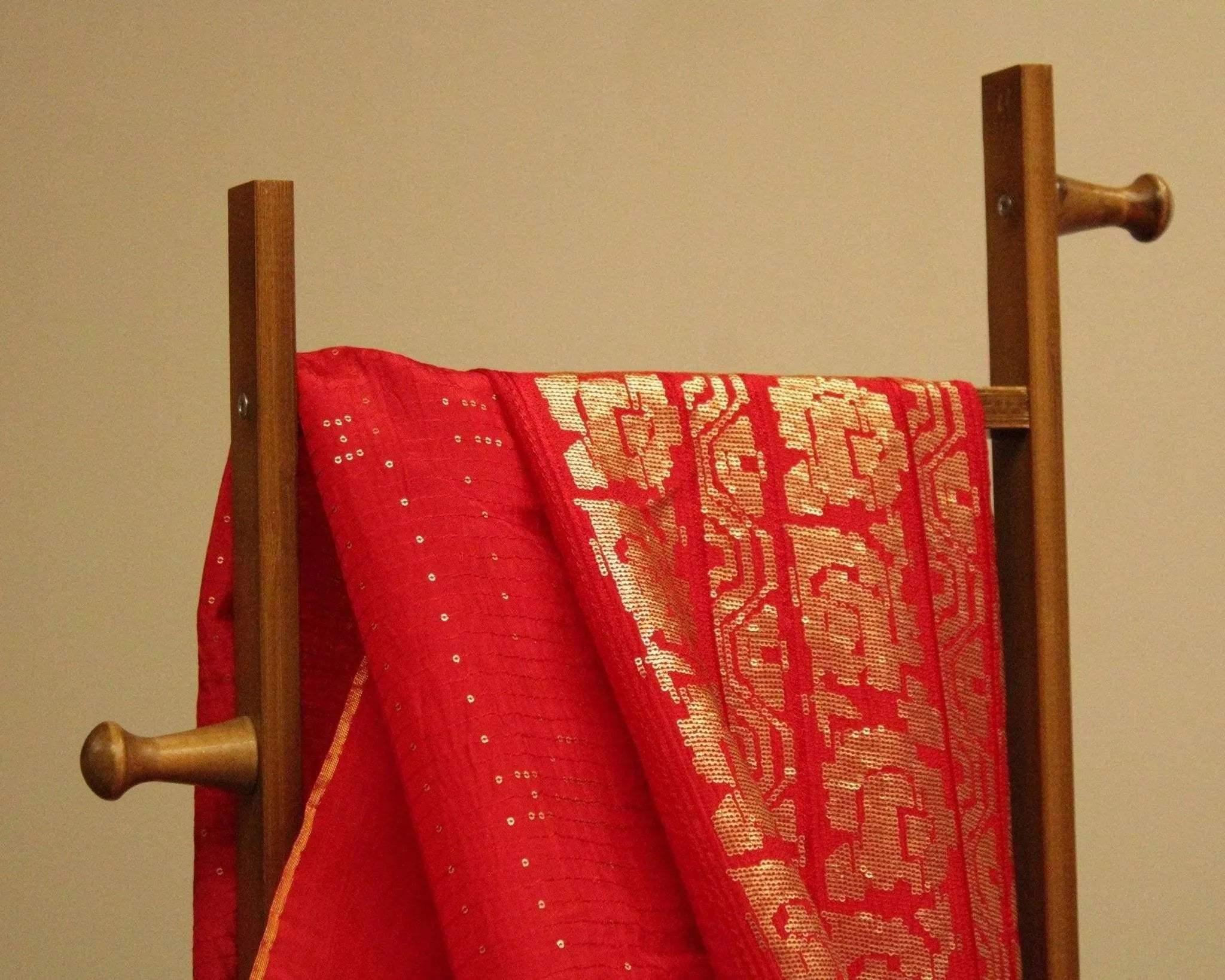 Red Upada silk fabric with gold micro work panel and sequin detailing draped on a wooden rack