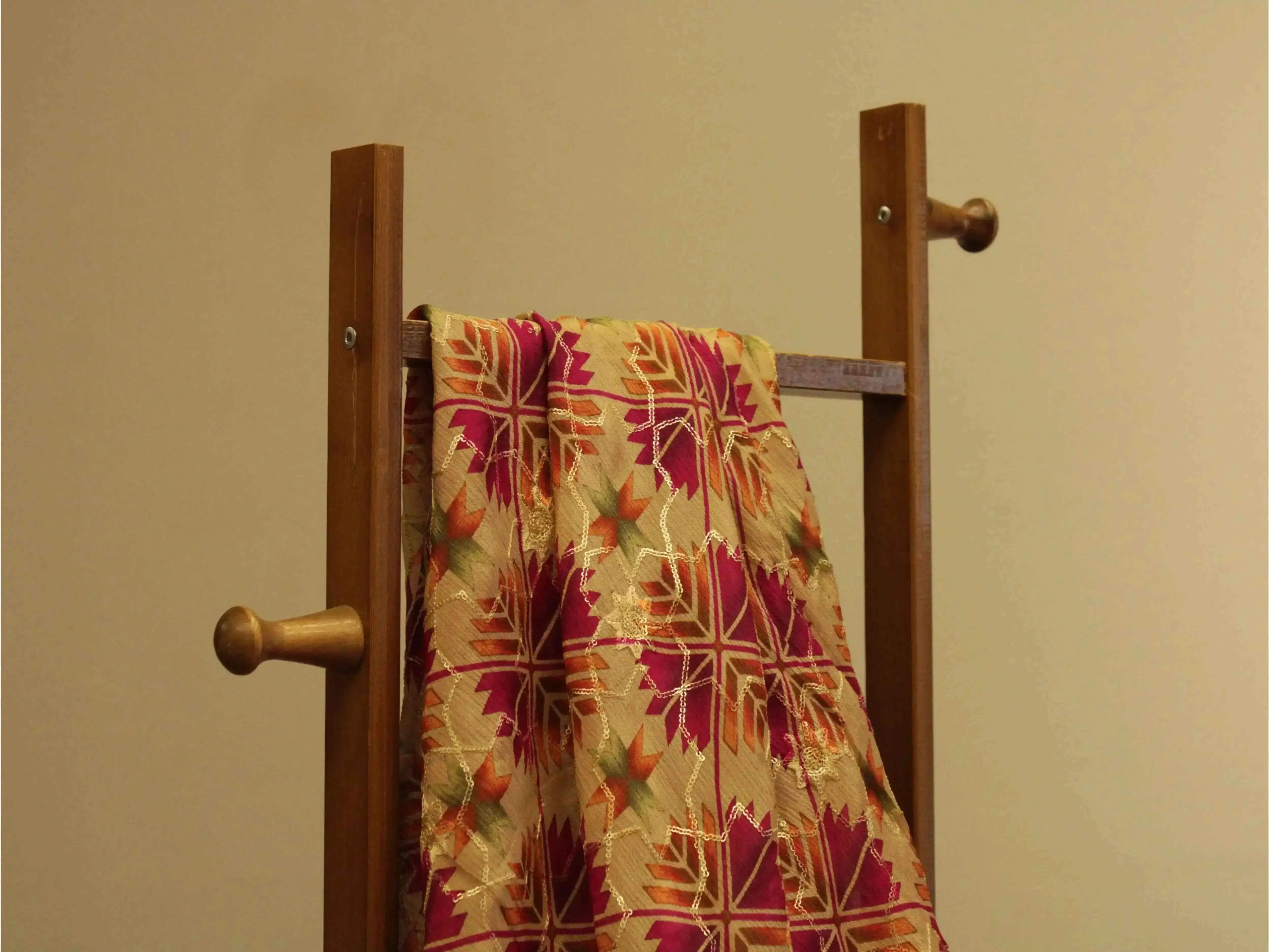 Vibrant digital Chinon silk fabric with geometric floral pattern draped on wooden rack