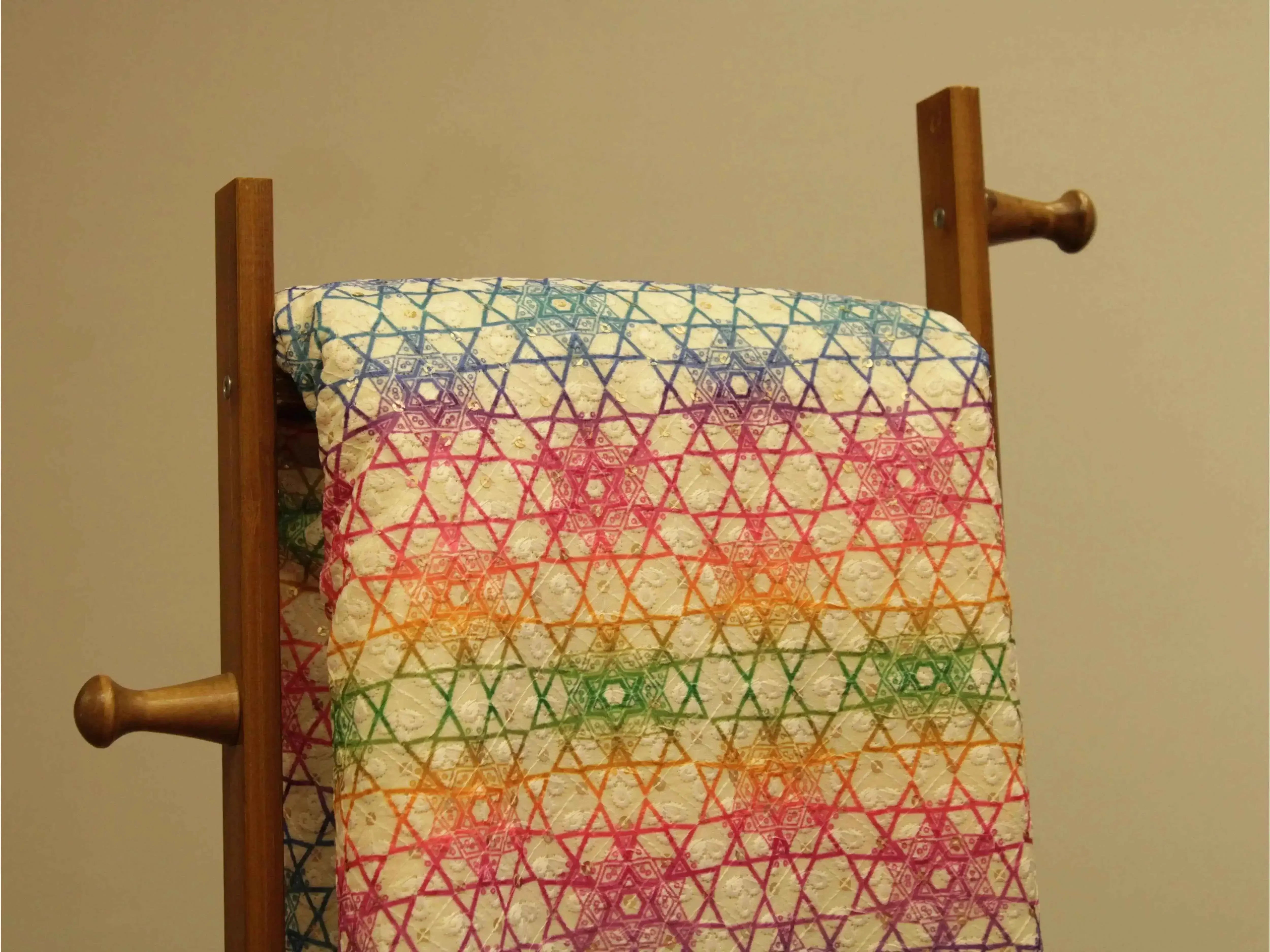 Vibrant digital silk fabric with multicolor geometric star patterns on display rack