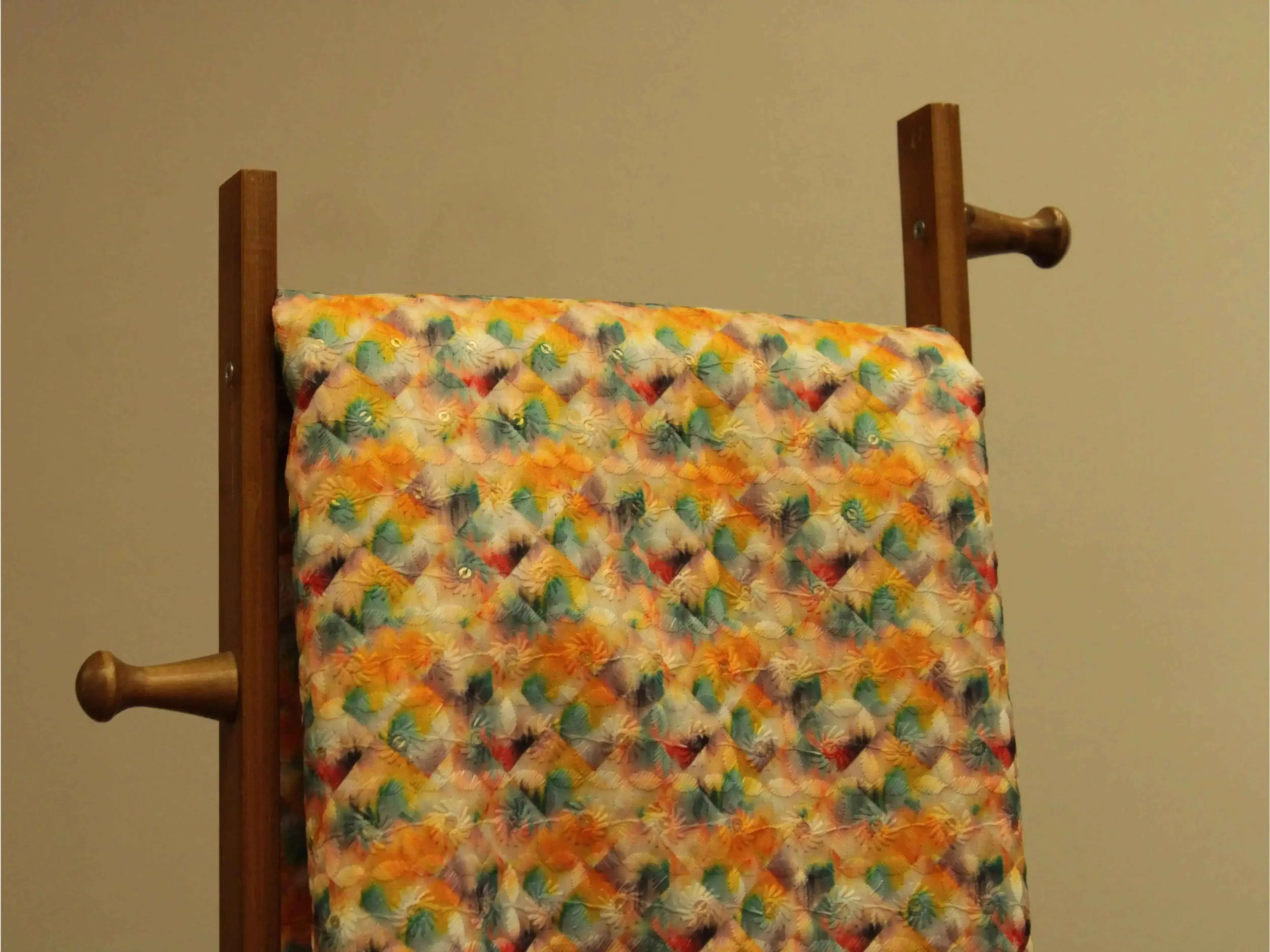 Colorful digital silk fabric with vibrant geometric floral pattern draped on wooden stand