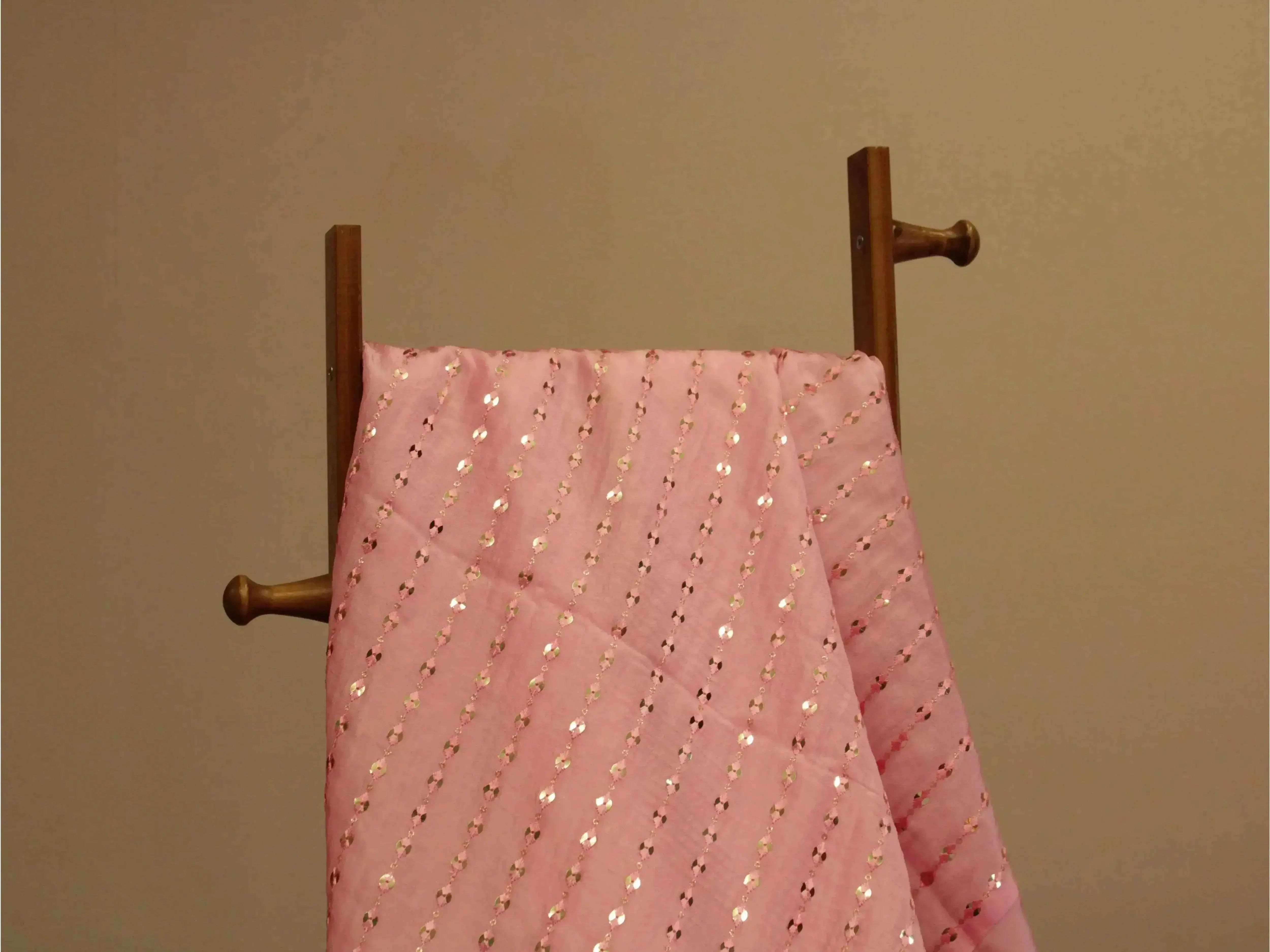 Pink mirror work fabric with diagonal sequin embroidery draped on wooden stand