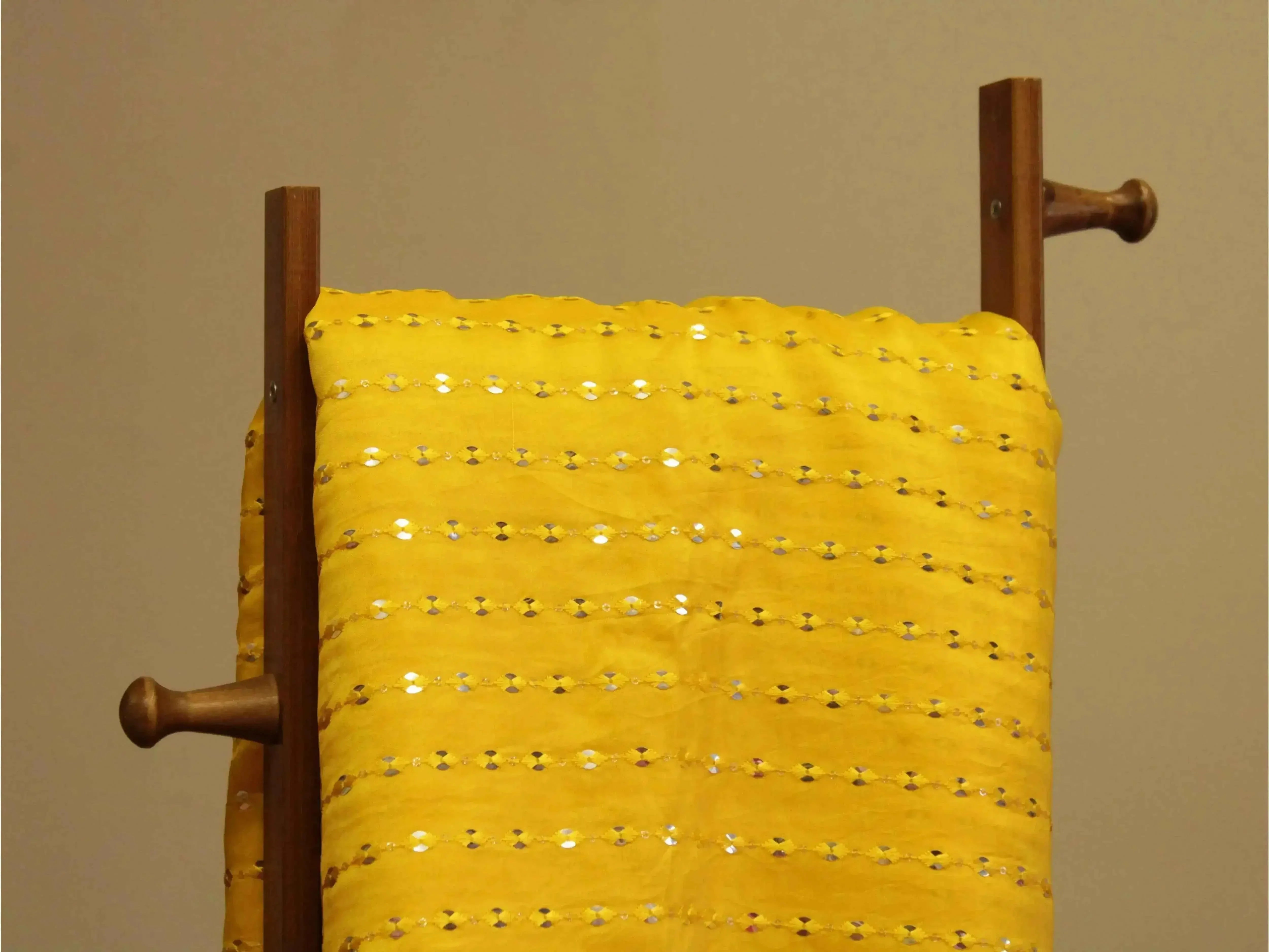 Yellow mirror work fabric with sequin details draped on a wooden stand