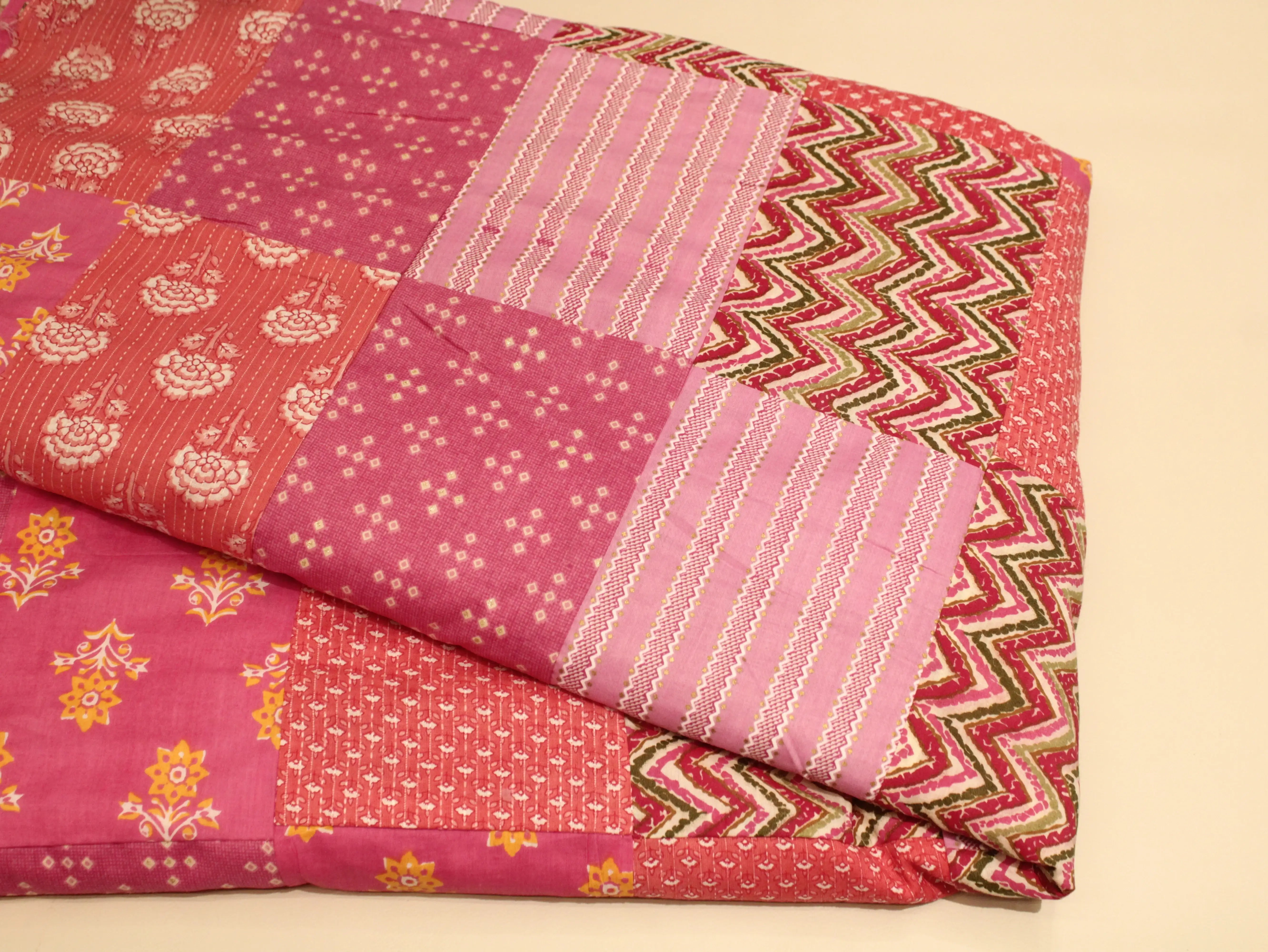 Stack of colorful fabric with various patterns on a beige background