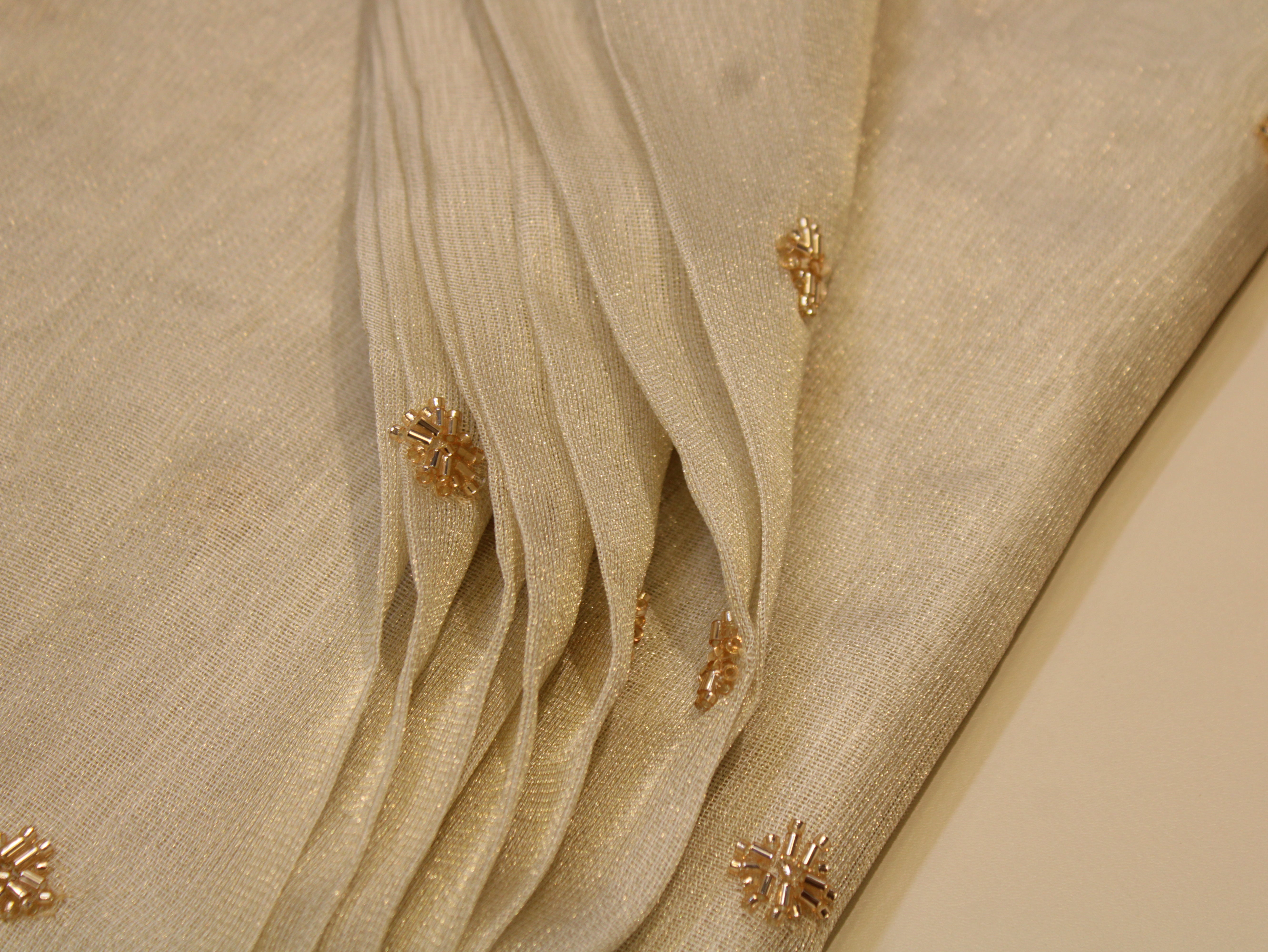 Beige fabric with gold floral embellishments on a beige background