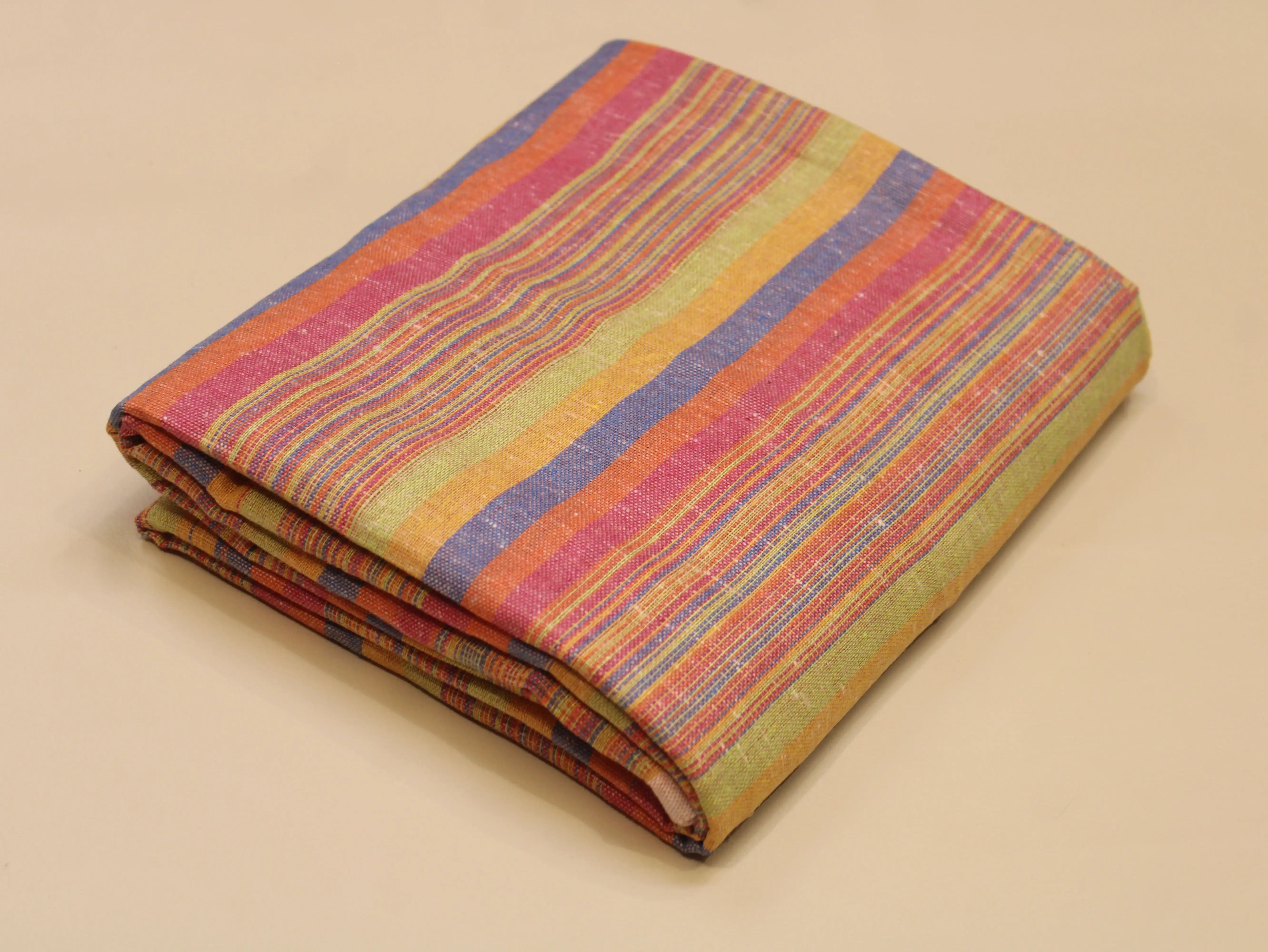 Folded multicolor striped cotton fabric on a beige background, ideal for ethnic wear.
